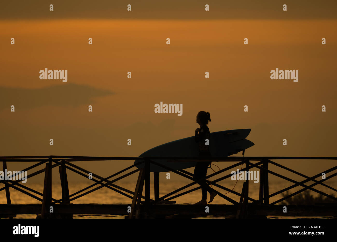 Daybreak als weibliche surfer Spaziergänge entlang der Promenade zum Surfen auf Wolke 9, Siargao, Philippinen Stockfoto