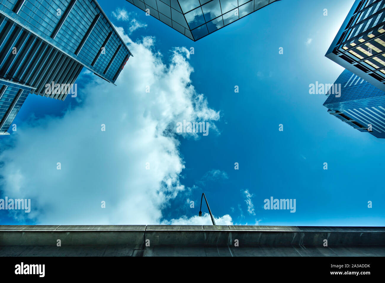 Blick auf blauen Himmel und weiße Wolken in einer engen Lücke zwischen steigenden anonymen, generischen Bürotürmen aus Glas in Sydney, Australien Stockfoto