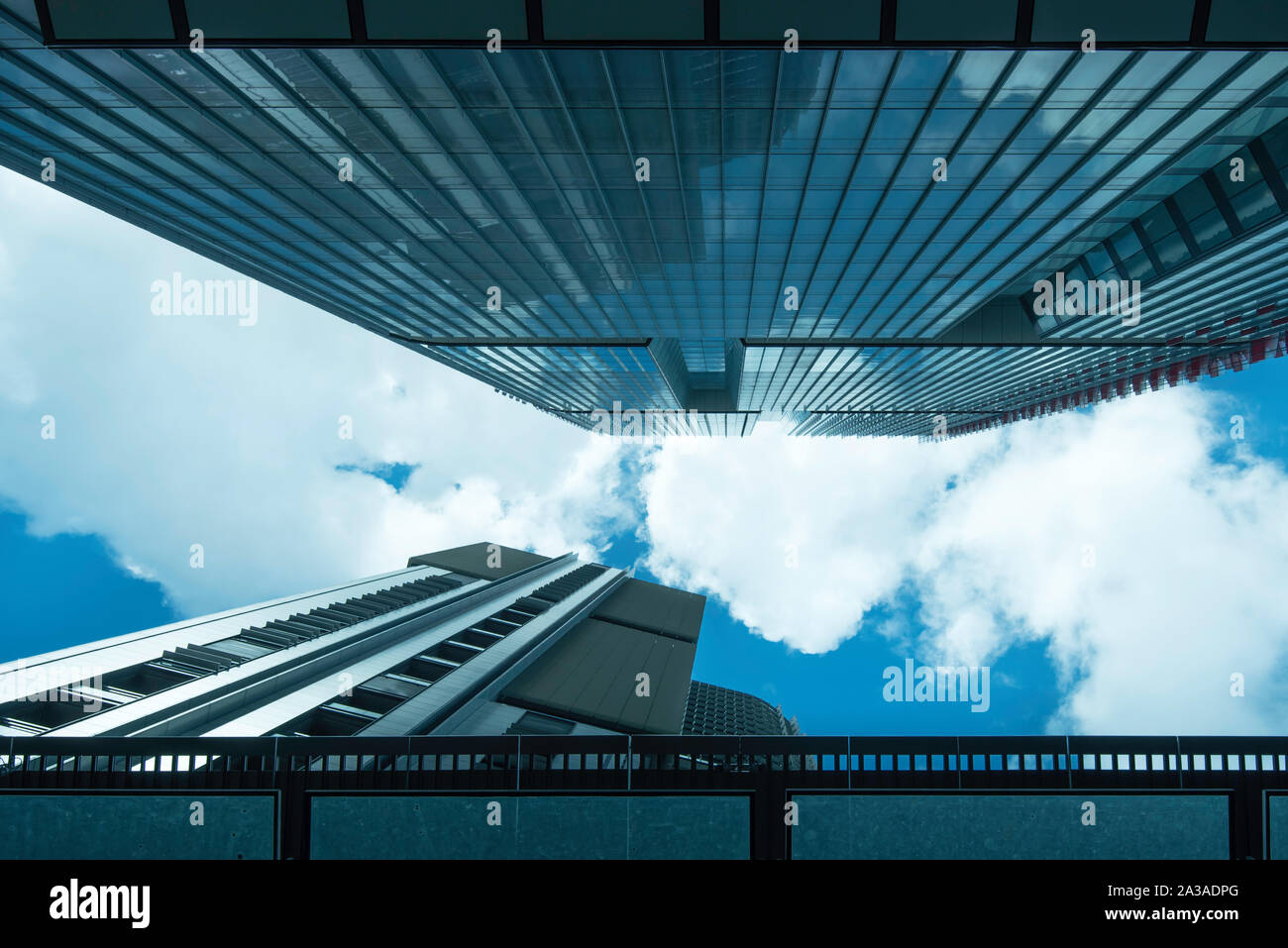 Schaut zum blauen Himmel und weißen Wolken in einen schmalen Spalt zwischen steigenden Glas Bürotürme in Sydney, Australien Stockfoto