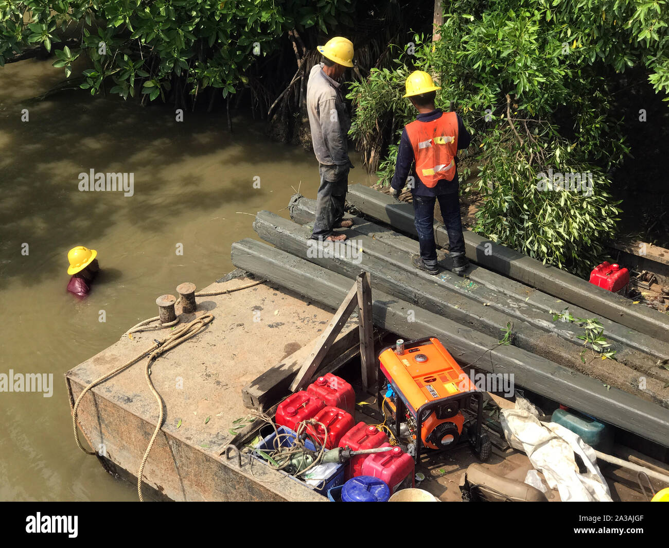 Team der Arbeitnehmer ziehen die Pfeiler aus dem Wasser auf dem Eisernen Steg. Fluss Küste Wiederaufbau, Thailand Stockfoto