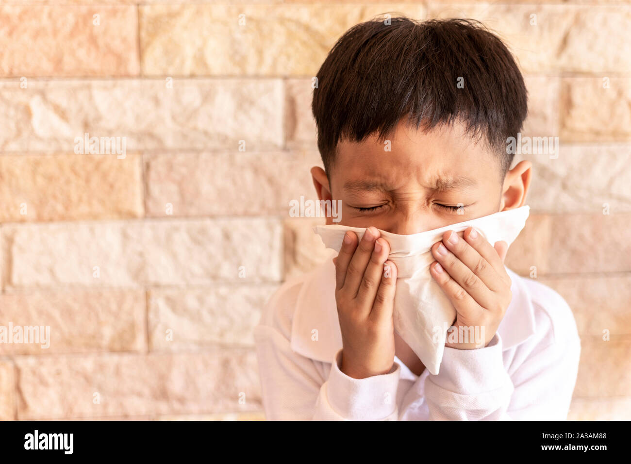 Gesundheit, kleiner Junge war krank mit einer runny Nase weht. Asiatische Kind blasen Nase mit einem Taschentuch zu Hause. Stockfoto