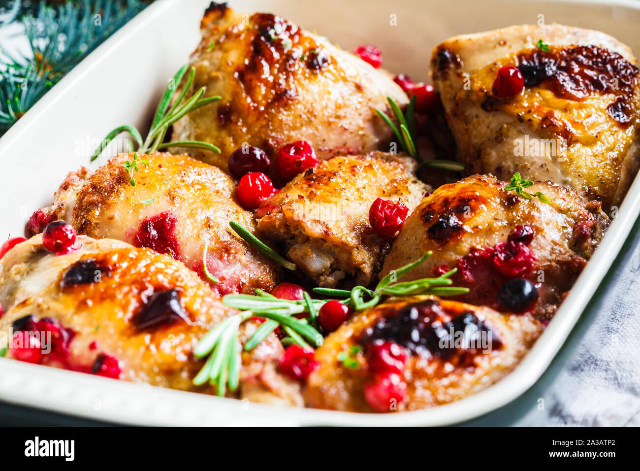 Weihnachten essen. Hähnchenfleisch gebacken mit Preiselbeeren und Rosmarin in die Auflaufform. Stockfoto