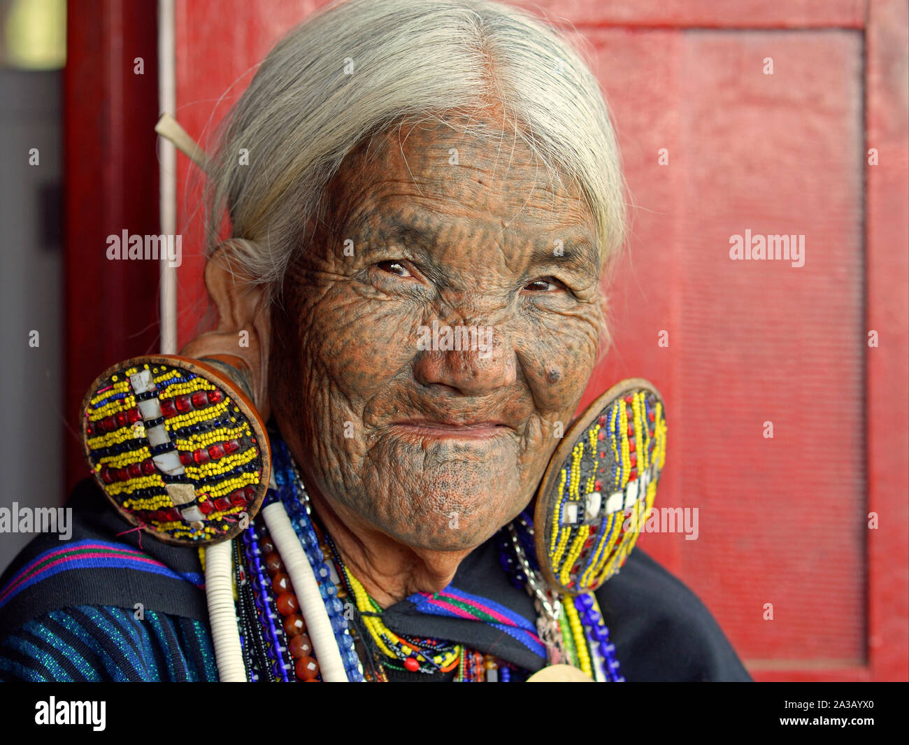 Alte Kinn Kaang Bergvolk Frau mit gepunkteten klassischen Gesichtsbehandlung Tattoo und aufwendige Tribal Ohrringe posiert für die Kamera (Kopf geschossen). Stockfoto