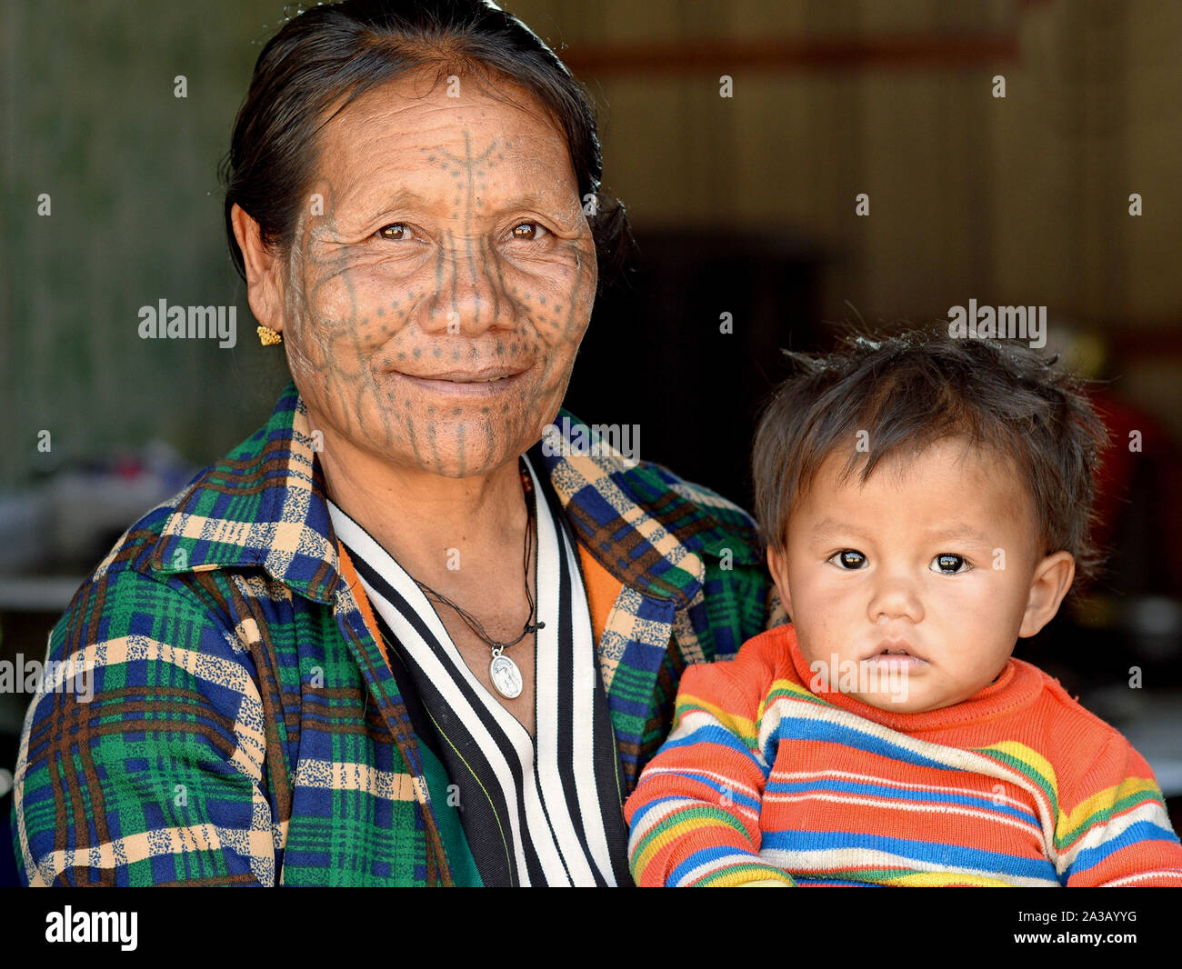 Ältere Kinn Muun tribal Frau ('Spider Frau') mit klassischen Gesichtsbehandlung tattoo Lächeln für die Kamera zusammen mit ihrem süßen kleinen Enkel. Stockfoto