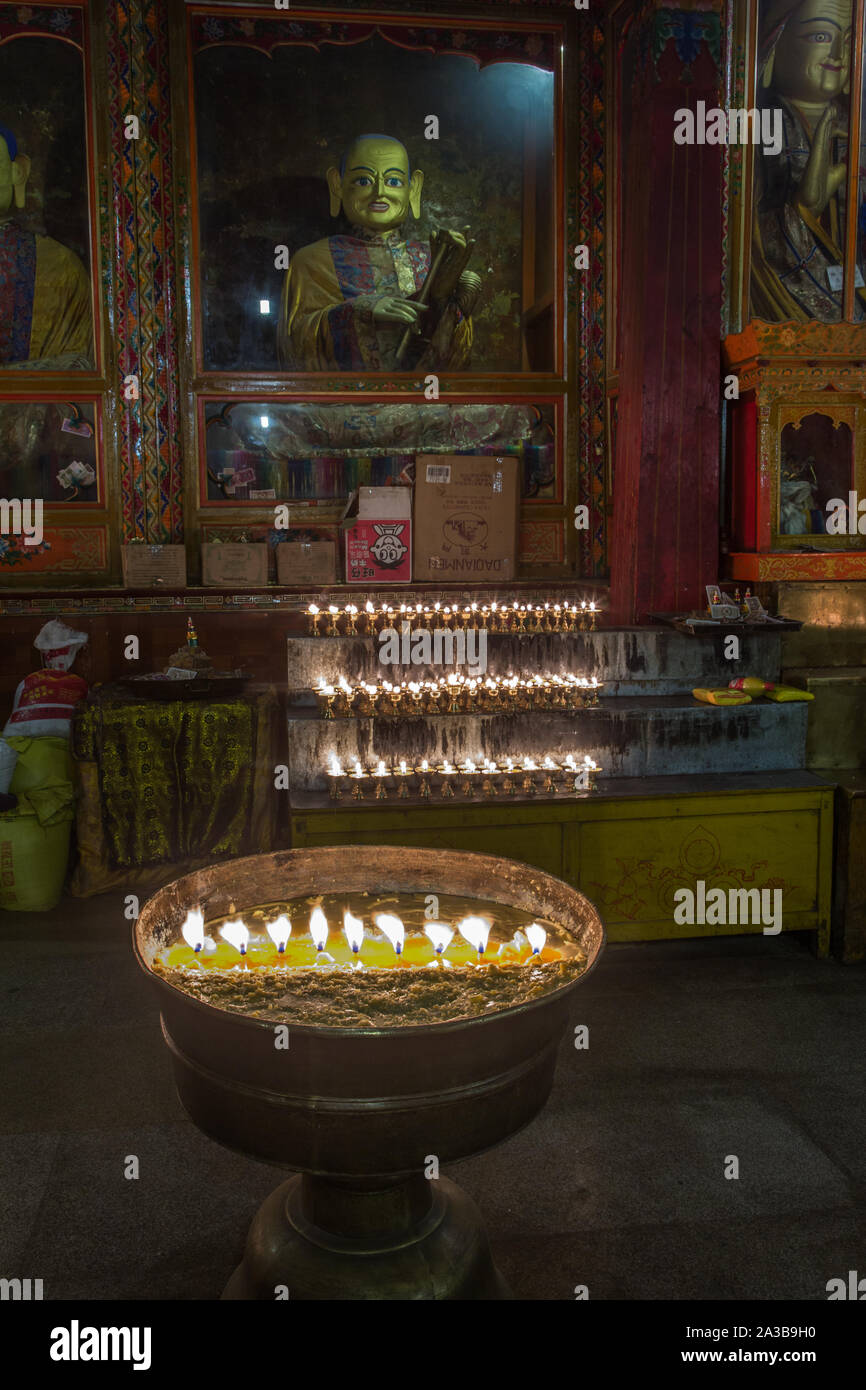 Yak butter Kerzen brennen als Opfer vor einem Buddha Statue im Kloster Ganden auf Wangbur Mountain in der Nähe von Lhasa, Tibet, gegründet 1409 A.D. Stockfoto