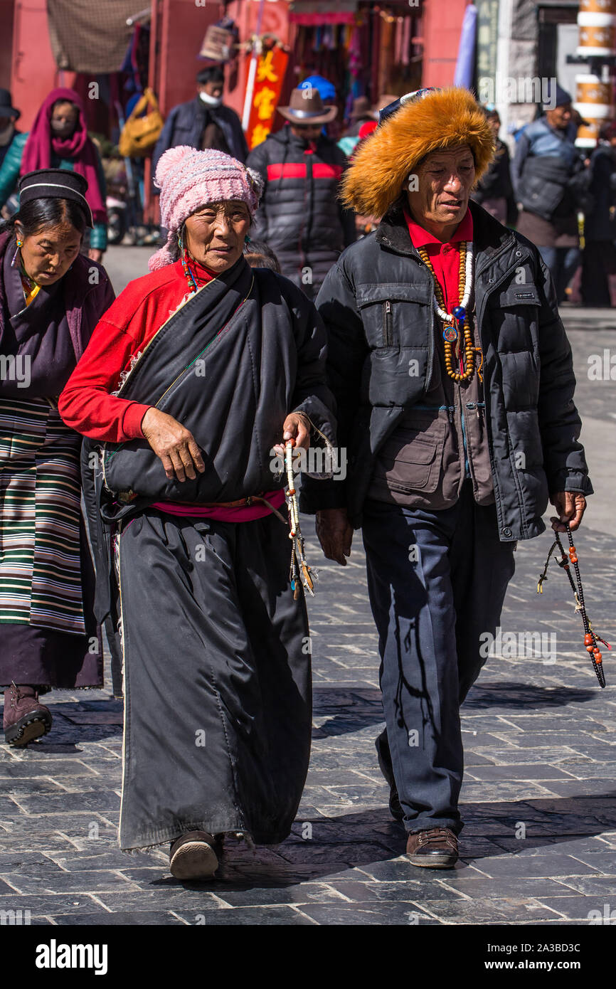 Tibetisch-buddhistische Pilger aus der Region Kham im Osten von Tibet gehen rund um den Jokhang Tempel in Lhasa, Tibet. Der Mann trägt einen roten Stockfoto