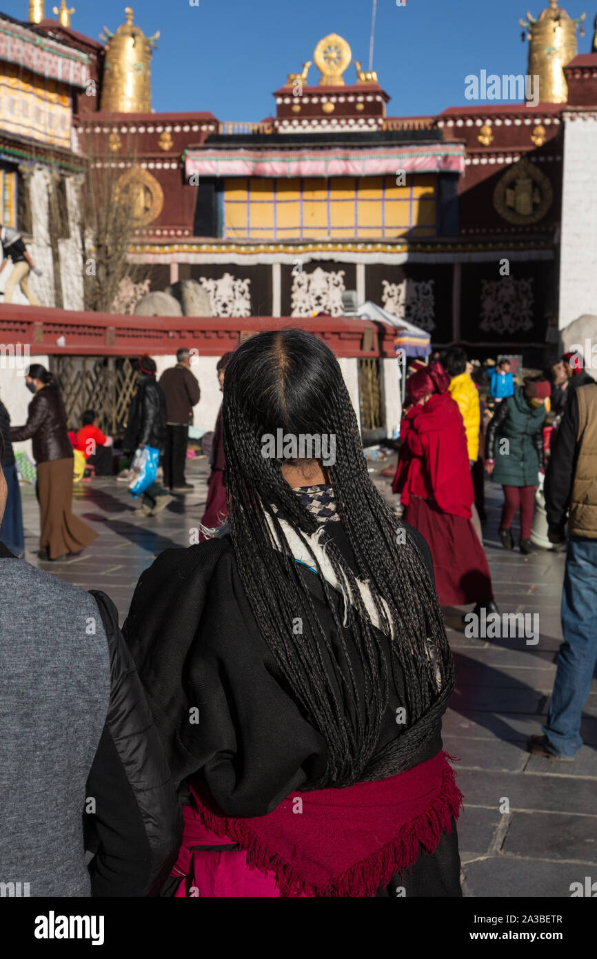 Eine ältere tibetische Frau pilgrim circumambulates den Jokhang Tempel mit ihrem Haar in kleinen Zöpfen. Lhasa, Tibet. Trägt den traditionellen chupa Gewand. Stockfoto