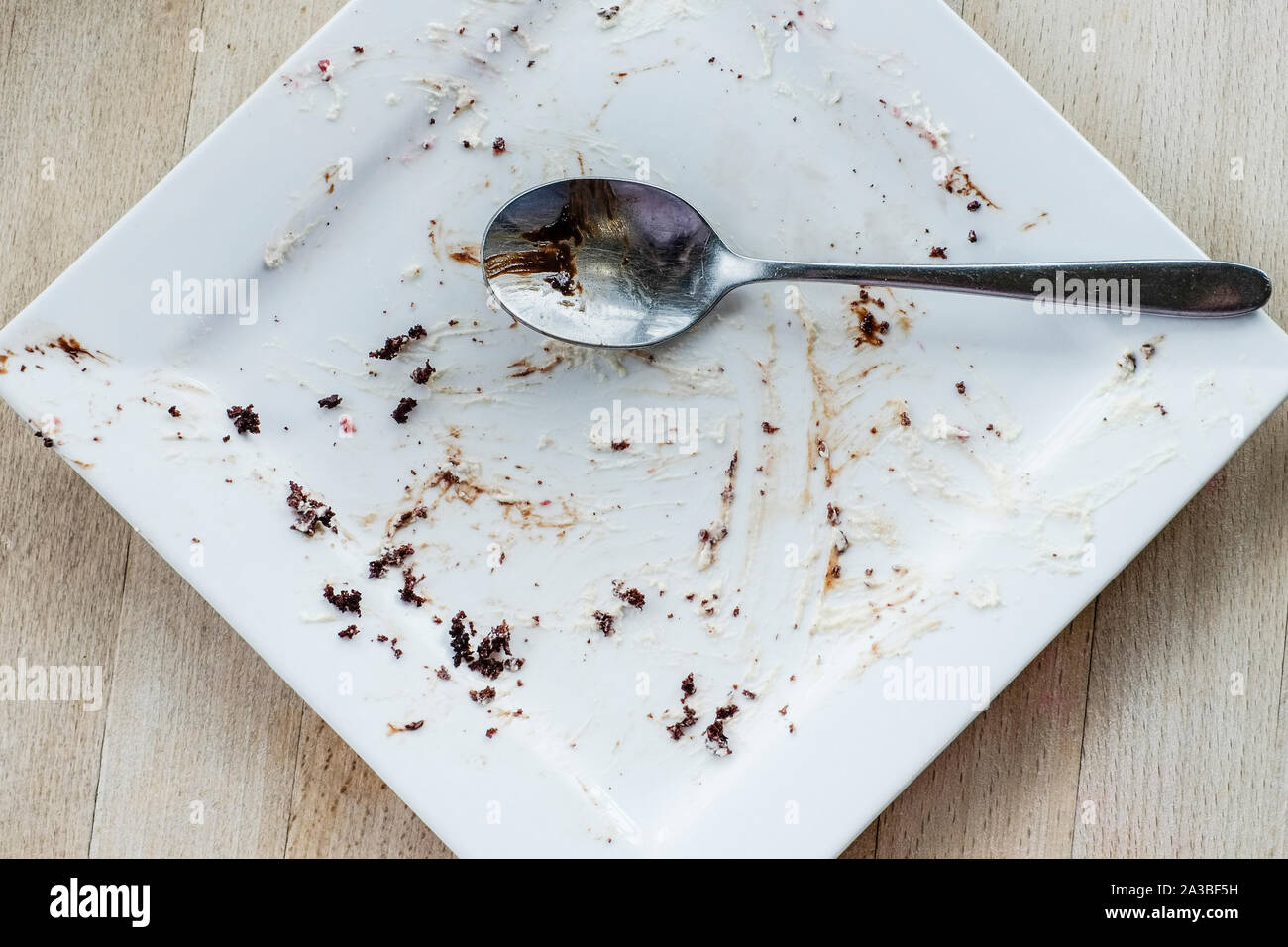 Eine Ansicht von einem Löffel auf einen leeren Teller nach einem Schokolade Dessert in einem restaurant gegessen wurde. Stockfoto