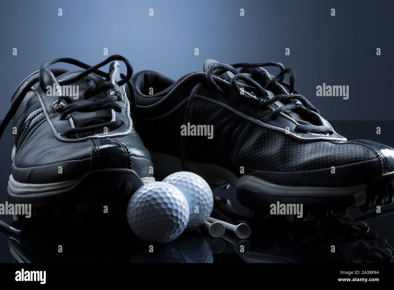 Golfbälle, Tees und Schuhe auf dunkelblauem Hintergrund isoliert. Stockfoto