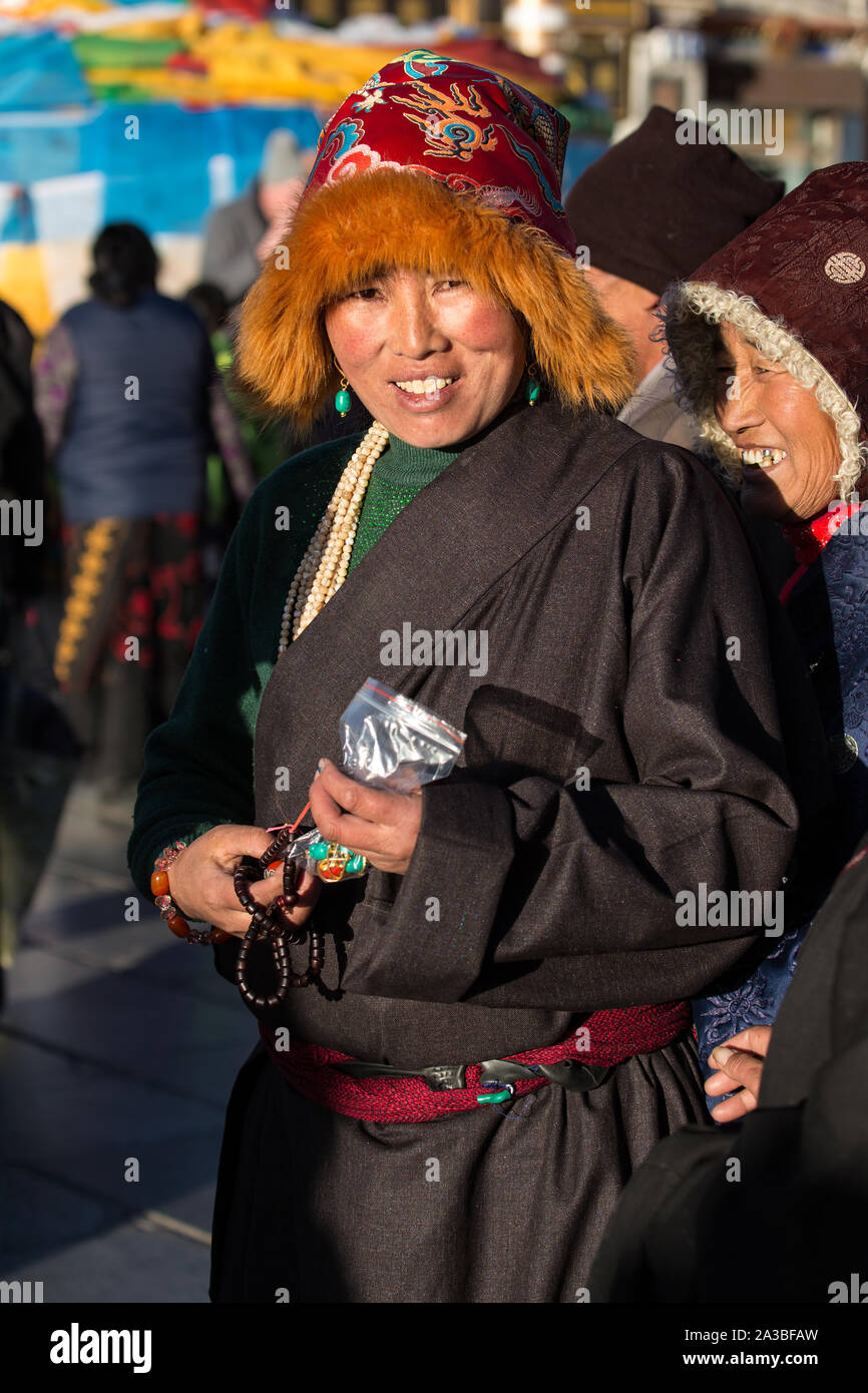 Eine junge tibetische Frau pilgrim circumambulates rund um den Jokhang Tempel, ihr mala Rosenkranz tragen und das Tragen eines traditionellen roten Fuchs Fell hat. Stockfoto