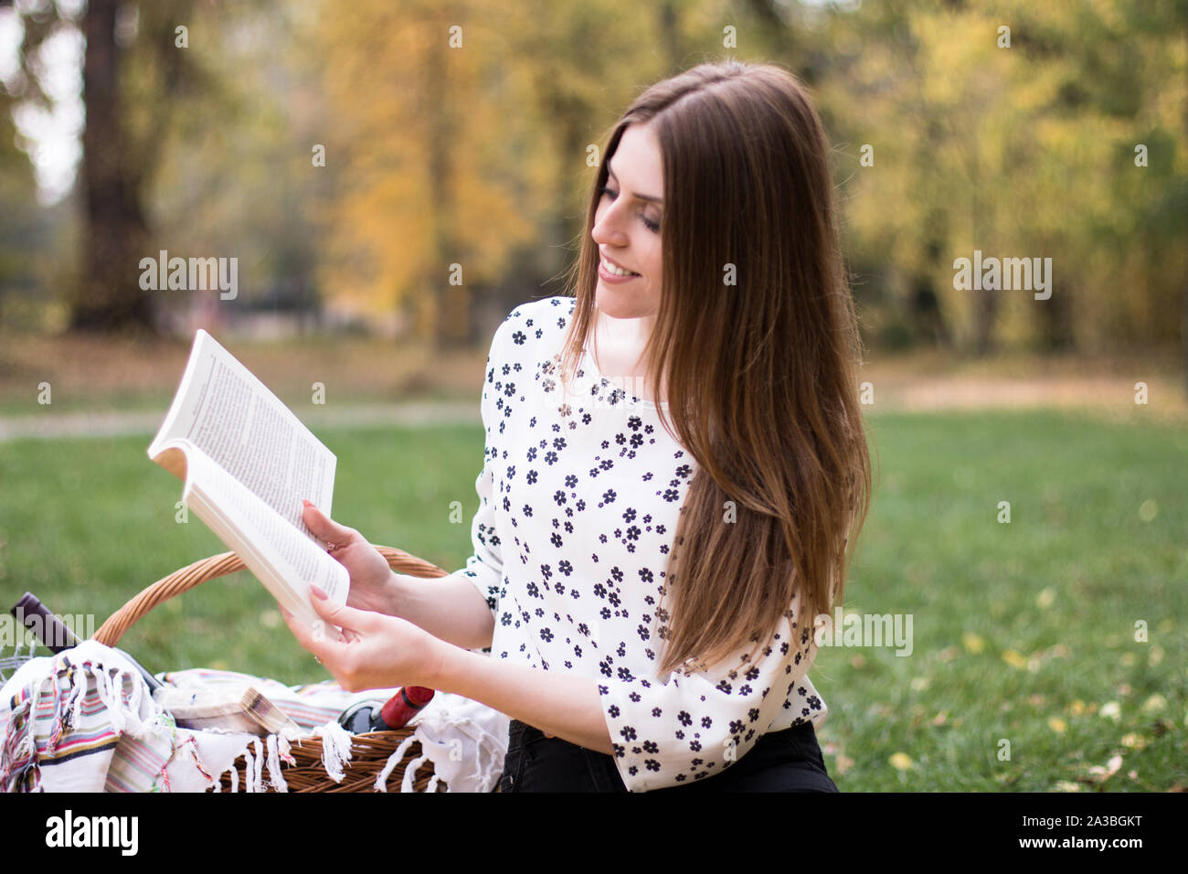 Junge hübsche kaukasische Frau mit einem Buch im Freien in den Park. Stockfoto
