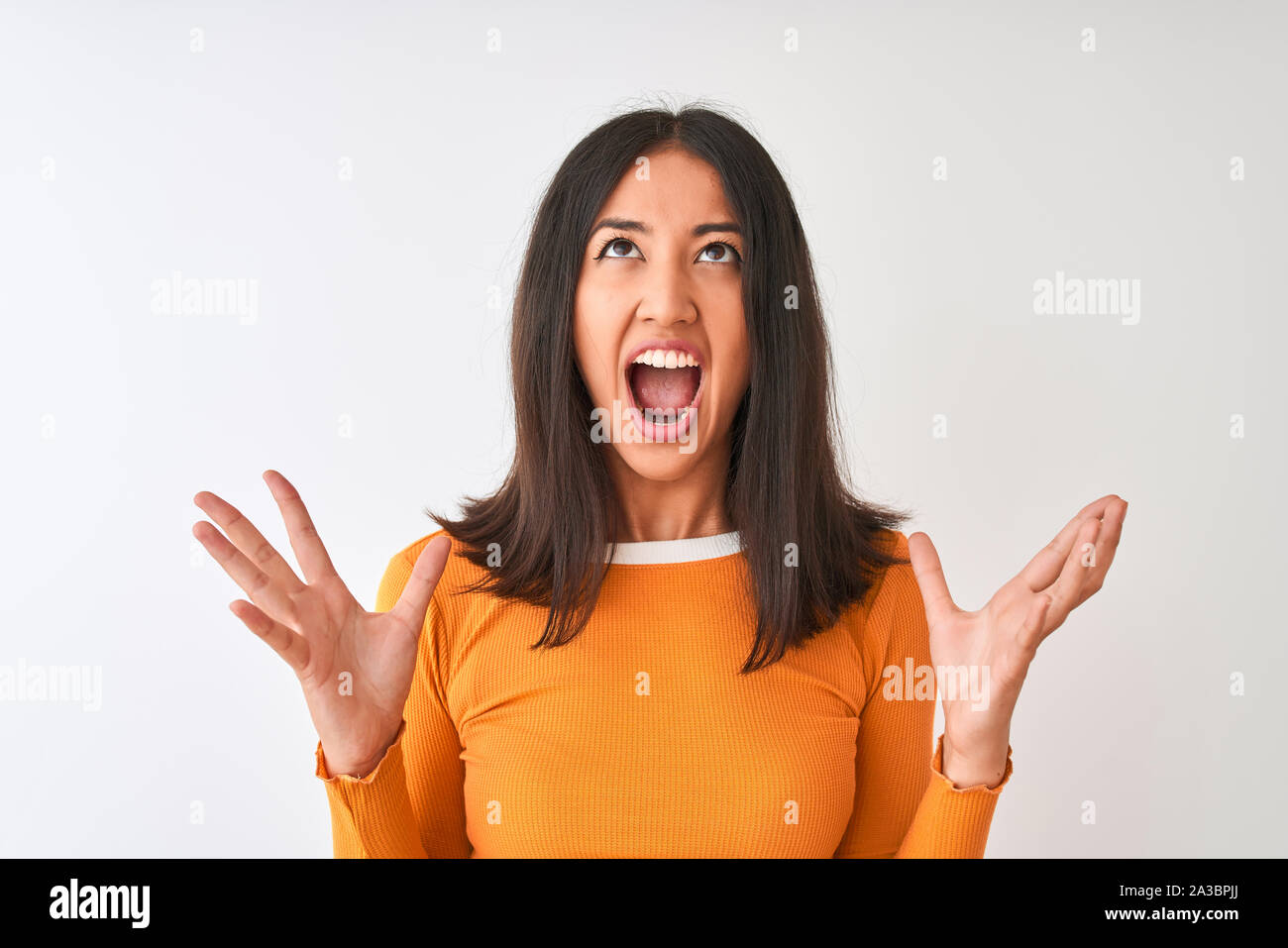 Junge schöne chinesische Frau tragen Orange t-shirt stehend über isoliert weißer Hintergrund verrückt und wütenden Schreien und Kreischen mit aggressiven Expres Stockfoto