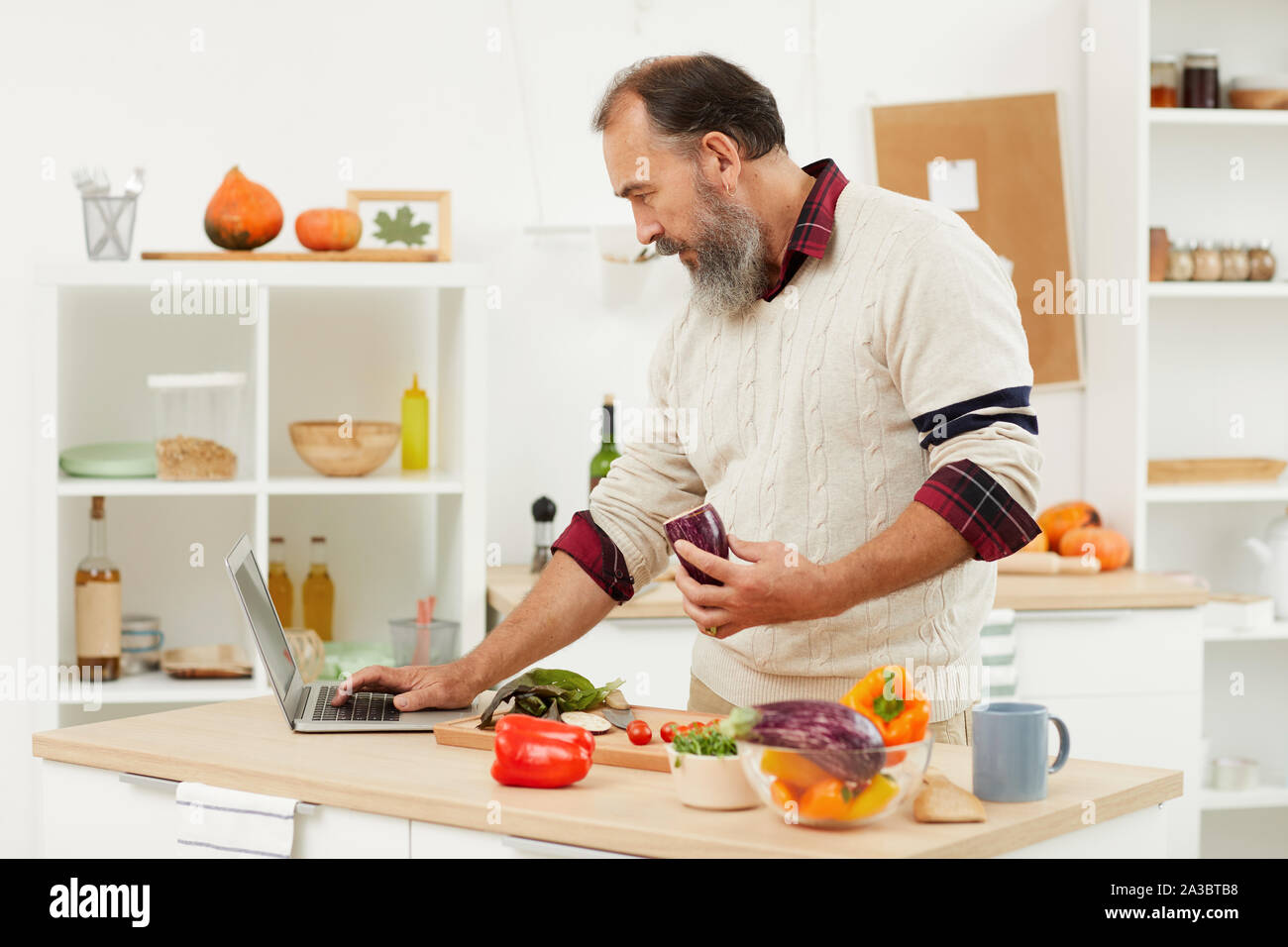 Taille bis Portrait von bärtigen Mann video Rezept per Laptop beim Kochen gesundes Essen in der Küche, kopieren Raum Stockfoto