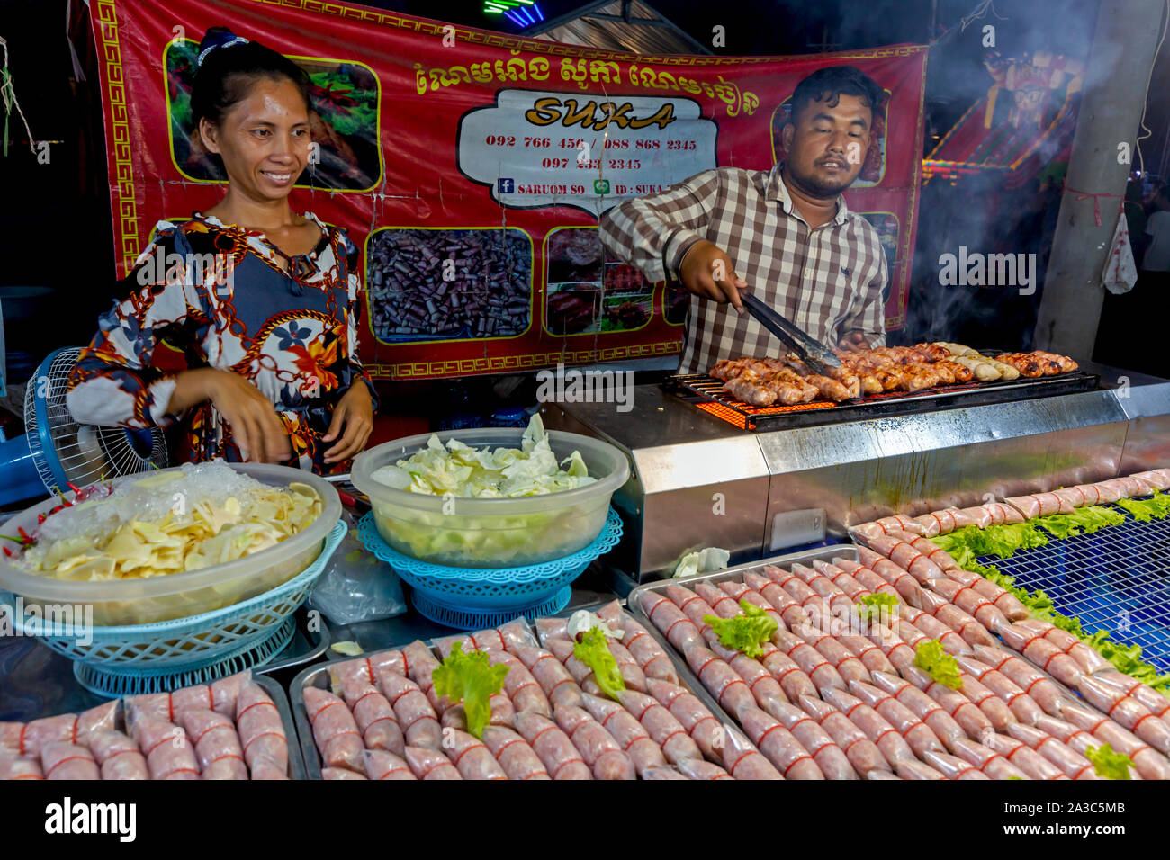 Ein Kambodscha Mann und Frau bereiten gegrilltes Fleisch auf einer Messe zu verkaufen und Messe in Kampong Cham, Kambodscha. Stockfoto