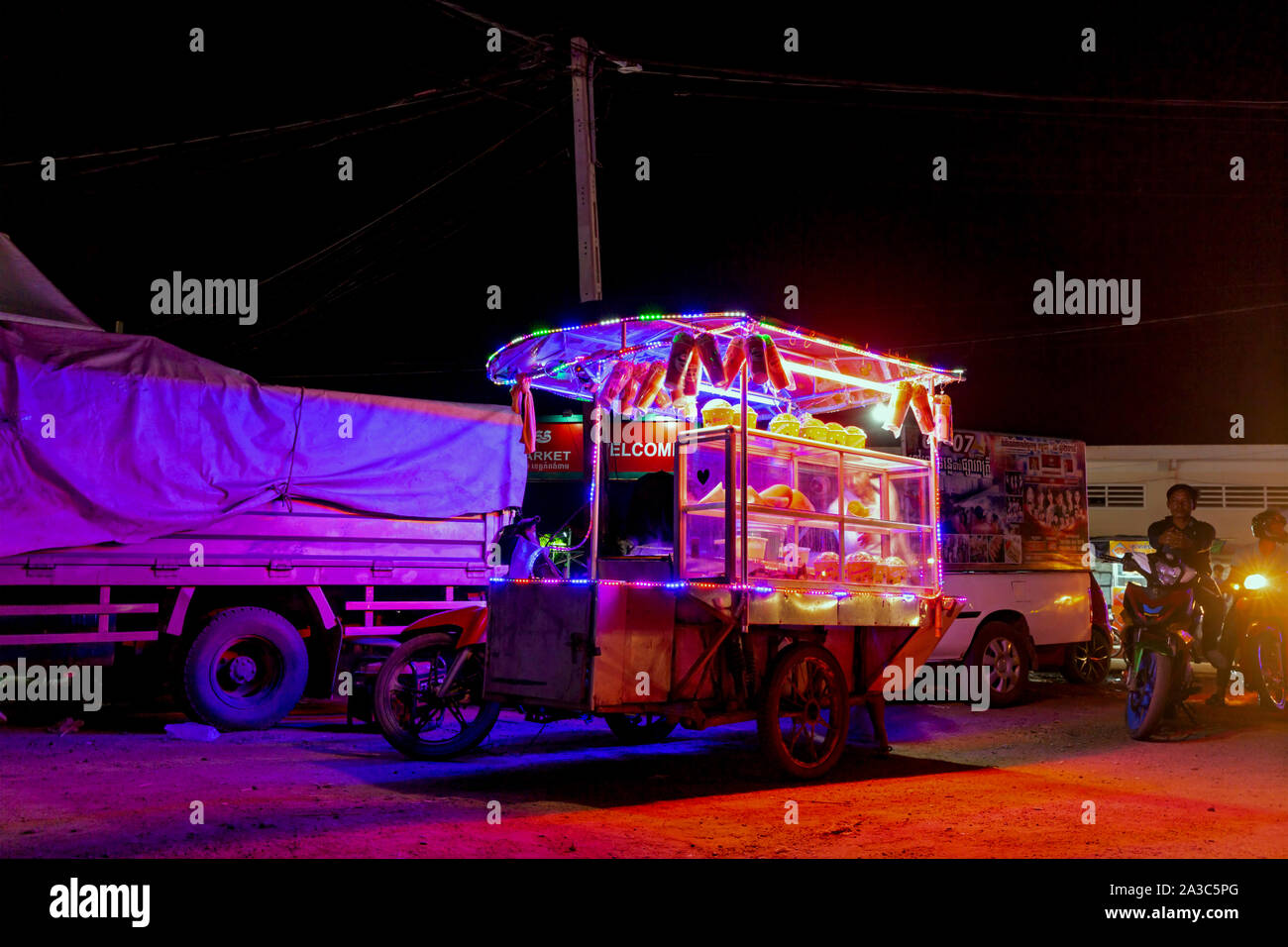 Ein Anbieter Verkauf von Popcorn von einer Karre auf einem Motorrad befestigt ist neben einem Karneval und Messe auf eine Stange in Kampong Cham, Kambodscha geparkt. Stockfoto