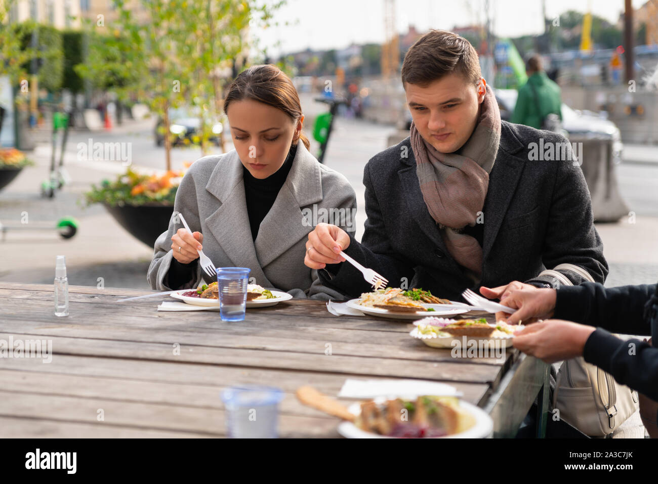 Junges Paar Essen mit Freunden oder der Familie an einem Tisch in einem Restaurant in einer Stadt Stockfoto