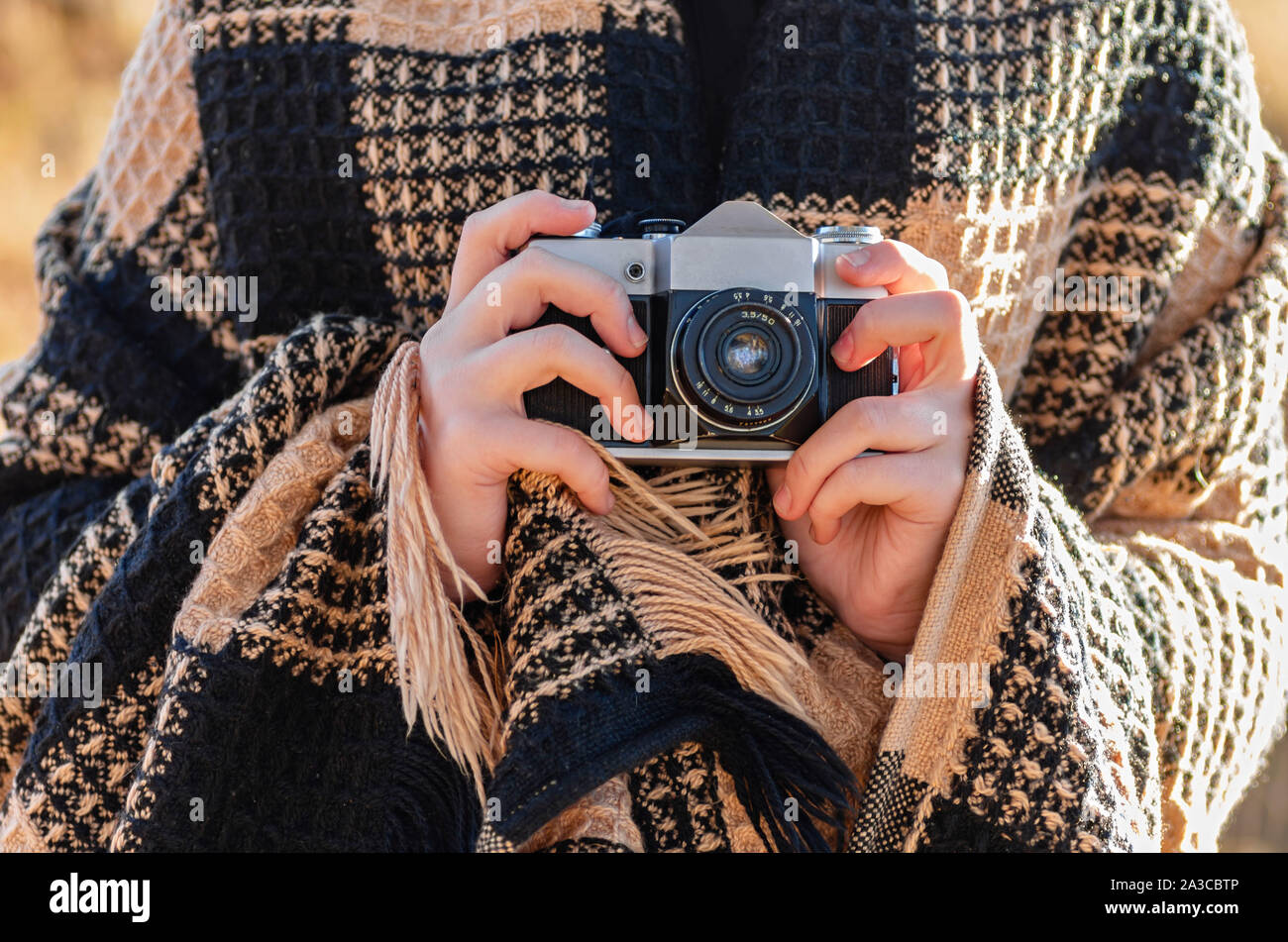 Outdoor Fotoshooting. Das Mädchen ist in einer warmen karierten Plaid  gewickelt und ist mit einem Vintage Kamera in den Händen. Close Up  Stockfotografie - Alamy