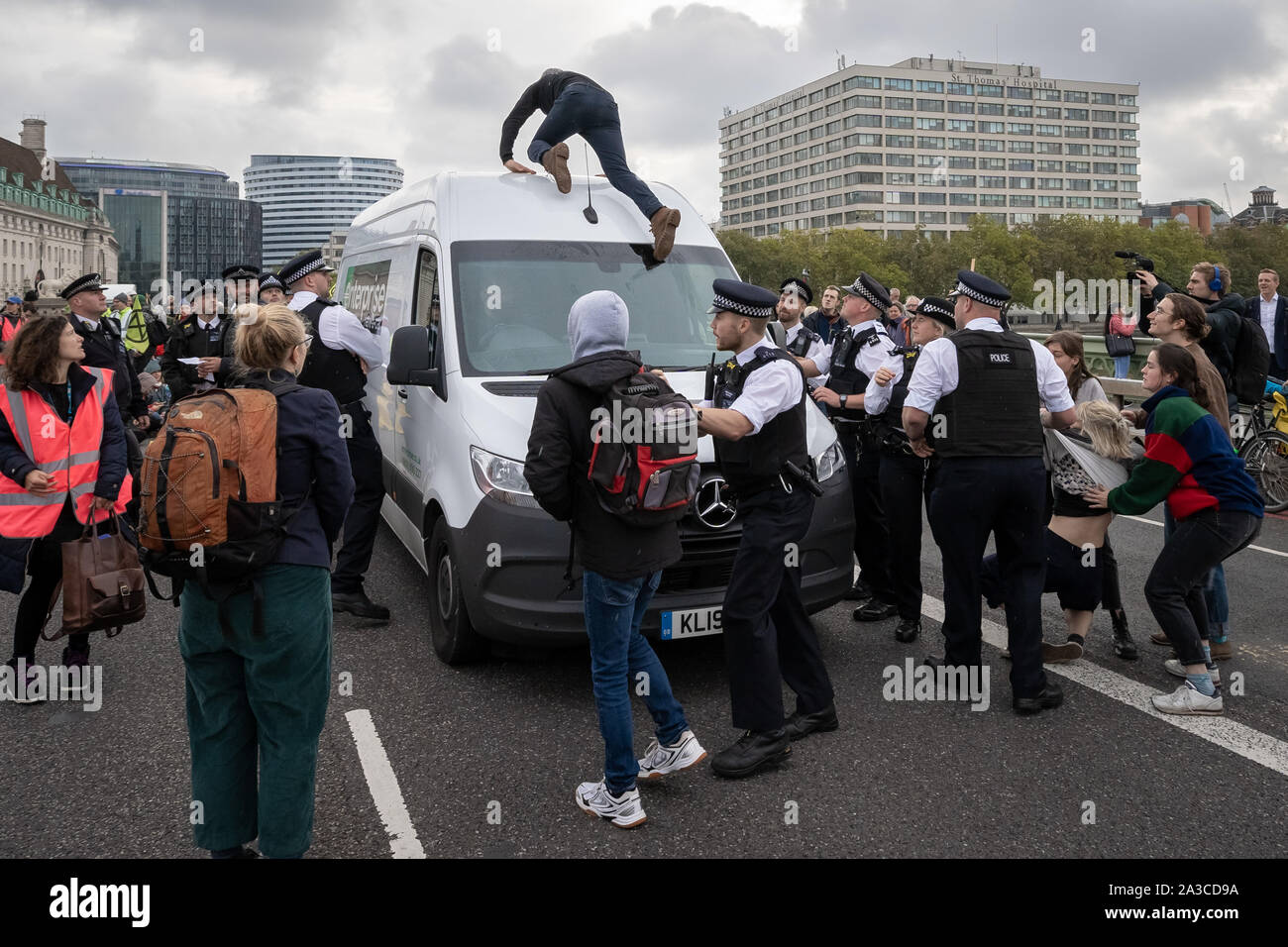 London, Großbritannien. 7 Okt, 2019. Eine Demonstrantin kriecht auf dem Dach als die Polizei einen Van der Ausrüstung vor dem Aussterben Rebellion Demonstranten nutzen wie Sie die Westminster Bridge besetzen. Die Umweltaktivisten beginnen Sie eine neue Welle von Protest Aktion heute Morgen verursachen Störungen in London. Der Metropolitan Police bestätigt 21 Verhaftungen so weit heute Morgen. Credit: Guy Corbishley/Alamy leben Nachrichten Stockfoto