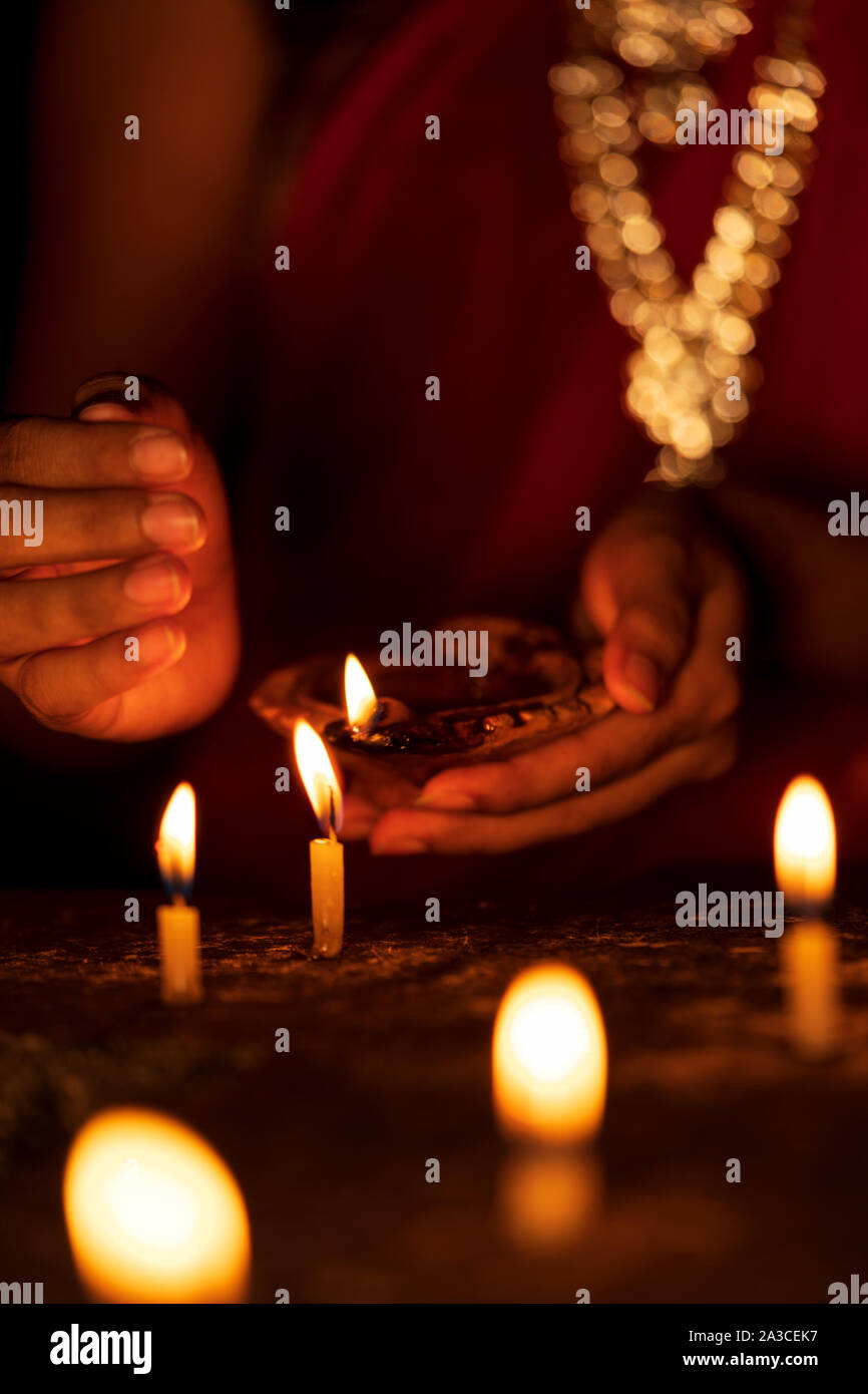 Schließen Sie herauf Bild der indischen Frau in der traditionellen saree Beleuchtung öl Lampe oder diya Feiern und diwali oder deepavali, Festival der Lichter am Tempel. Weiblich Stockfoto