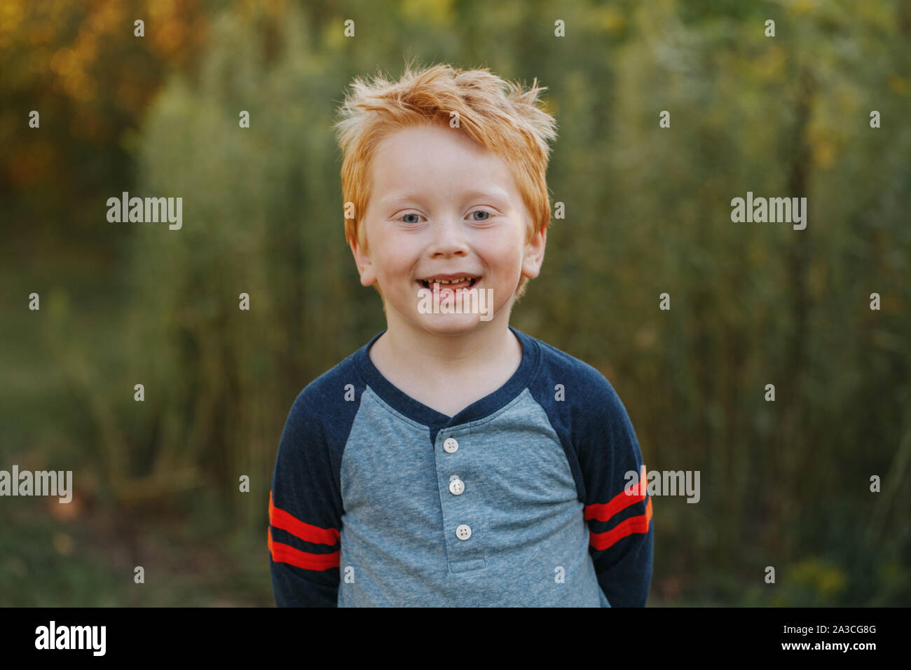 Closeup Portrait der kaukasischen Rothaarige niedlich aussehenden Vorschule Junge. Adorable Kind stehen draußen auf Herbst Tag. Glücklich lächelnde Kid outdoor. Ein Stockfoto