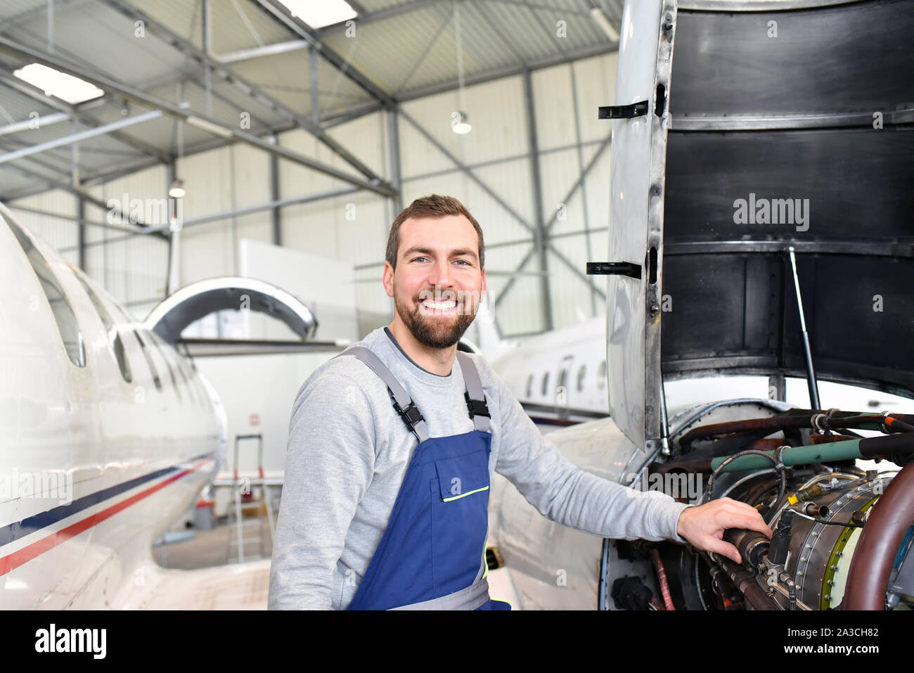 Portrait einer flugzeugmechaniker in einem Hangar mit Jets am Flughafen - Kontrolle der Flugzeuge für Sicherheit und Technische Funktion Stockfoto