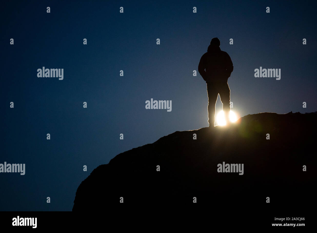 Ein Mann steht auf einem Felsen und Uhren ein super Mond auf einer Feder Nacht. Stockfoto