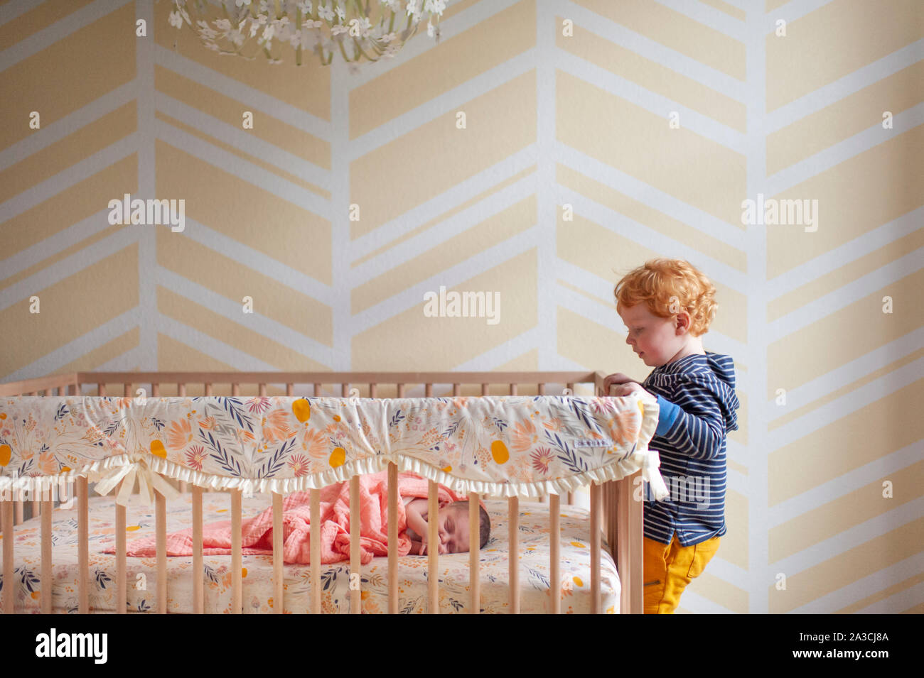 Toddler boy peeking in über Krippe Schiene bei neugeborenen Babys schlafen in der Krippe Stockfoto
