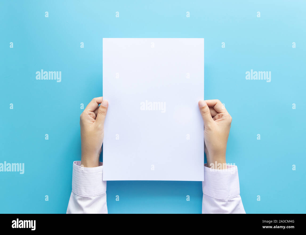 Die Hände schließen Holding leere weiße Leere schreiben Papierformat A4 für Flyer oder Einladung mock up auf einem blauen Hintergrund. Stockfoto