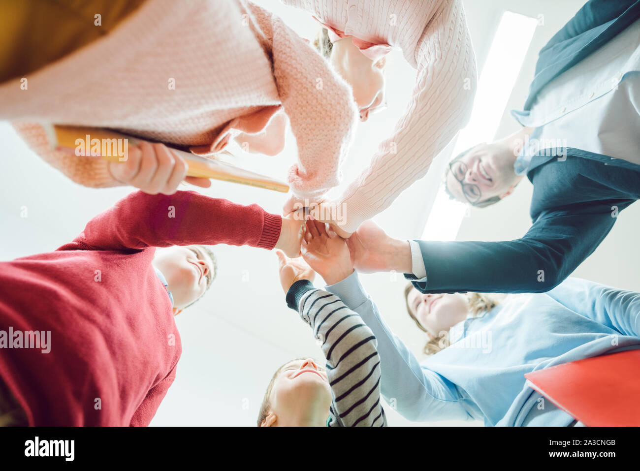 Schüler und Lehrer stapeln Hände als Team in der Schule Stockfoto