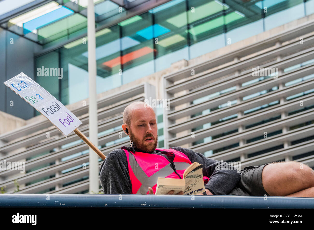 Ein Mann sitzt oben lesen Kritische Masse - ein Lkw blockiert die Straße vor dem Home Office und Demonstranten, die sich auf IT-Aussterben Rebellion Kette beginnen im Oktober Aktion die Straßen im Zentrum Londons für bis zu zwei Wochen blockieren. Sie sind einmal hervorheben, das Klima, mit der Zeit den Planeten vor einer Klimakatastrophe zu speichern. Dies ist Teil der laufenden ER und andere Proteste zu handeln, die von der britischen Regierung auf die "klimakrise" verlangen. Die Aktion ist Teil einer international koordinierten protestieren. Stockfoto