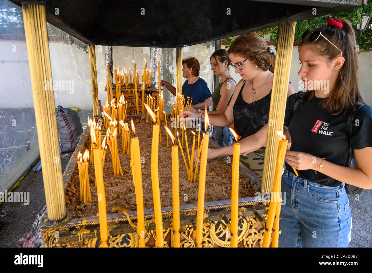 Junge Frauen Beleuchtung Kerzen in einem orthodoxen Schrein während eines Festivals in der Stadt Messini, Peloponnes, Griechenland. Stockfoto