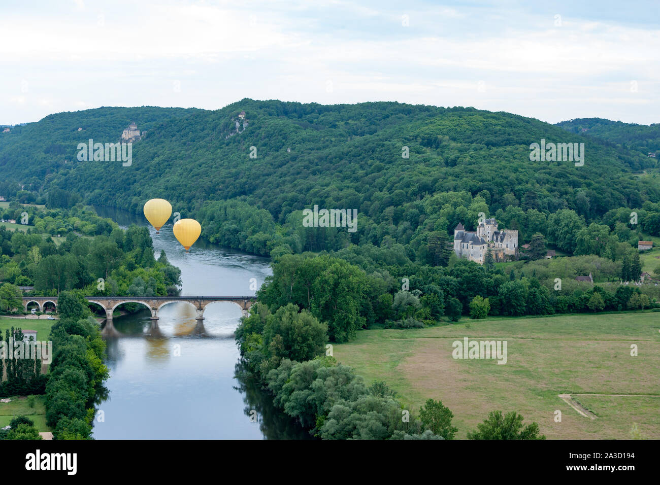 Zwei gelbe Luftballons fliegen über den Fluss Dordogne Frankreich mit chateau Castlenaud und Chateau Feyrac im Hintergrund Stockfoto