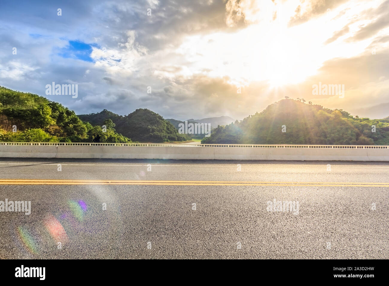 Asphaltierte Straße Seitenansicht mit Grüner See, schöne Himmel und lens flare in Betong, Yala, Thailand Stockfoto