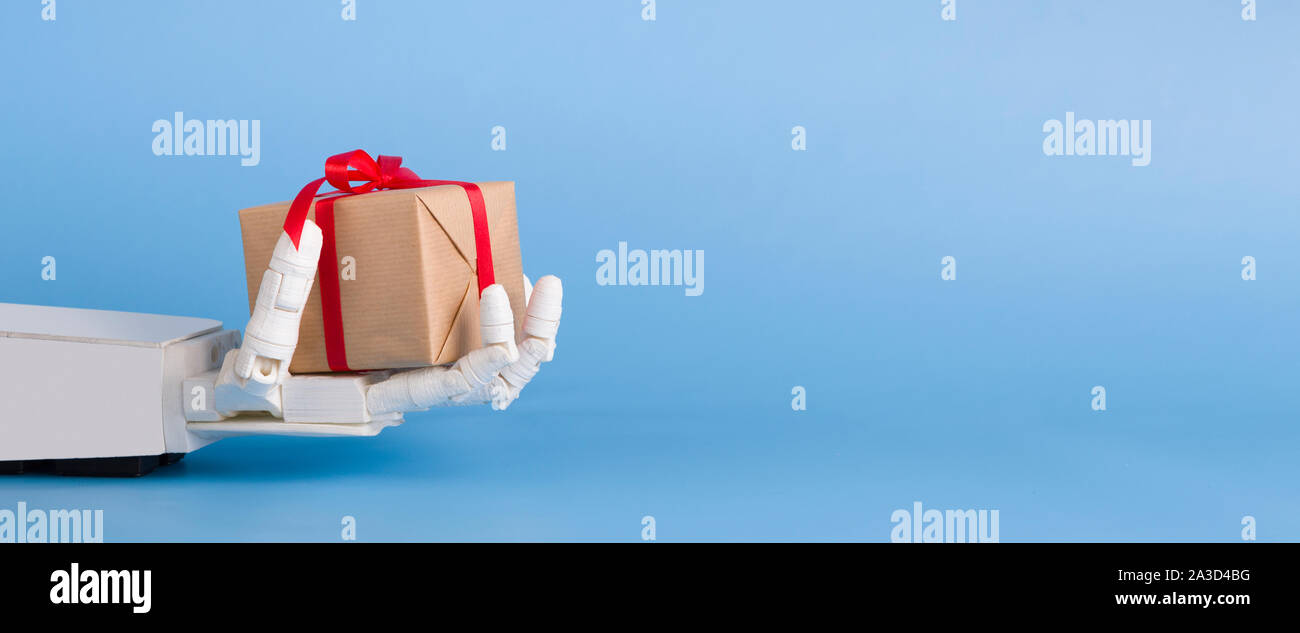 Geschenkbox in Automated Robot Hand, blauer Hintergrund Stockfoto