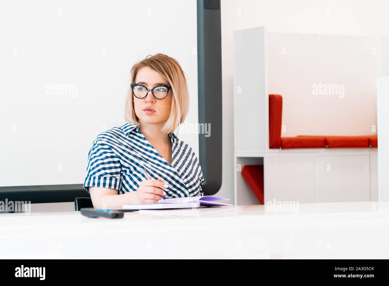 Junge nachdenklich attraktive Professorin mit Brille in formelle Kleidung Lehre an Klasse und eine Prüfung abzulegen. sitzen in der Nähe der Tafel. Stockfoto