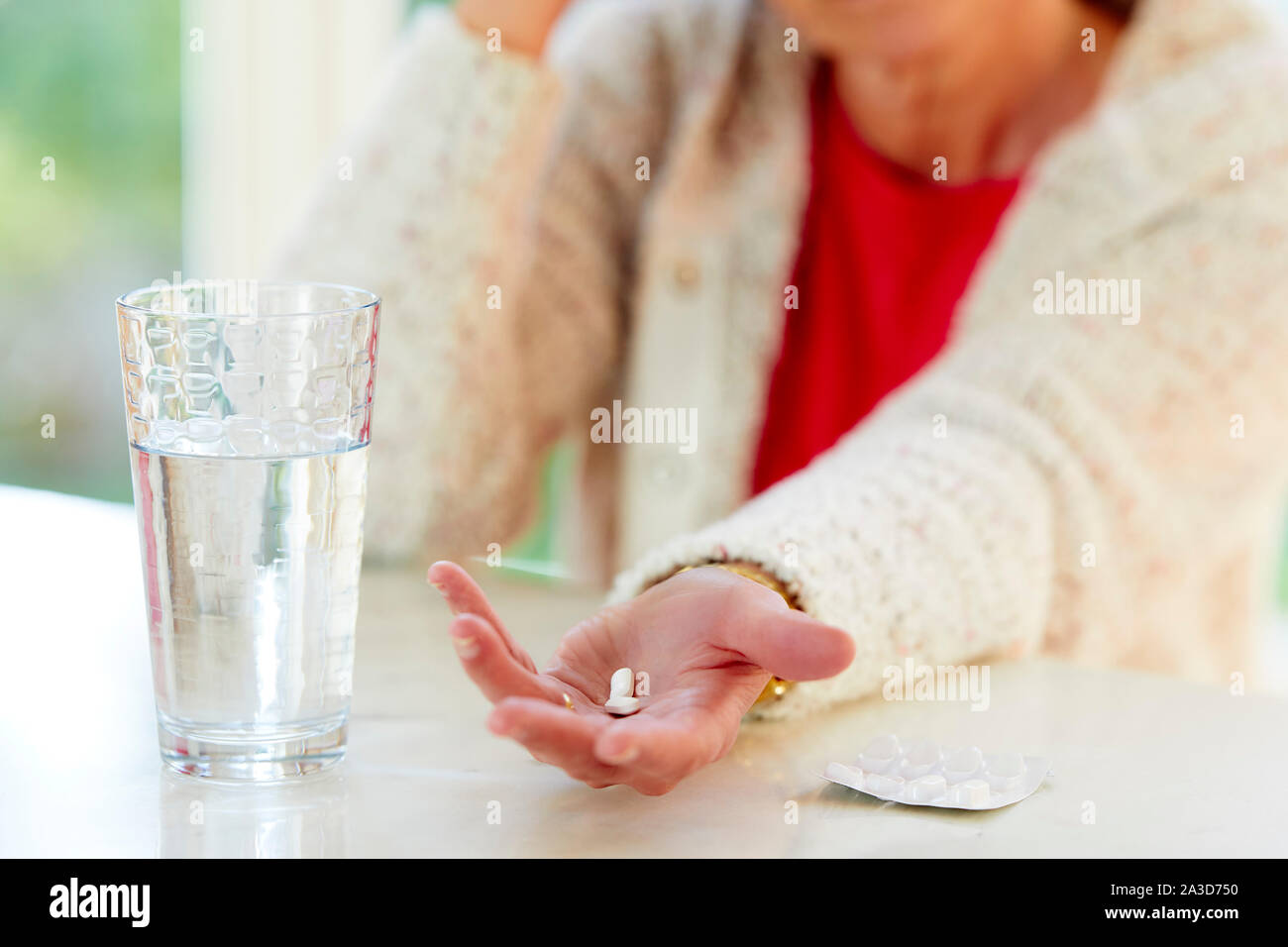 Frau mit Tabletten mit einem Glas Wasser. Stockfoto