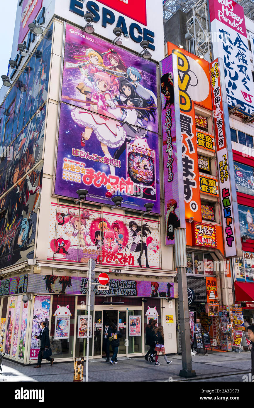 Tokio, Akihabara. Espace Gebäude mit großen Werbetafeln von Big eyed junge Frauen anime Figuren neben Orange außen auf DVD speichern. Menschen zu Fuß, Stockfoto