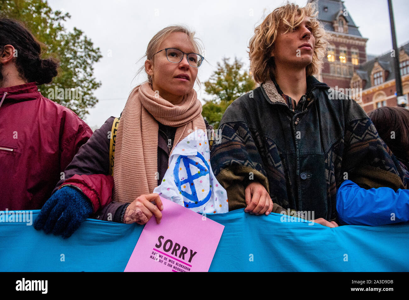 Ein XR Aktivist hält eine XR Flyer während der Demonstration. Für 2 Wochen, Aussterben Rebellion und verwandter Bewegungen werden in den großen Städten auf der ganzen Welt sammeln und weiterhin rebellieren gegen die Regierungen der Welt für ihre kriminellen Untätigkeit auf das Klima und die ökologische Krise zu. XR Klima Aktivisten in Amsterdam werden eine große Blockade über mehrere Tage auf der Museumbrug zu organisieren, vor dem Rijksmuseum. Von früh am Morgen, Hunderte von XR Aktivisten zeigte auf der Brücke, wo es mit einem sichtbaren polizeilichen Präsenz. Die Umweltorganisation aussterben Rebellion will die Du Stockfoto