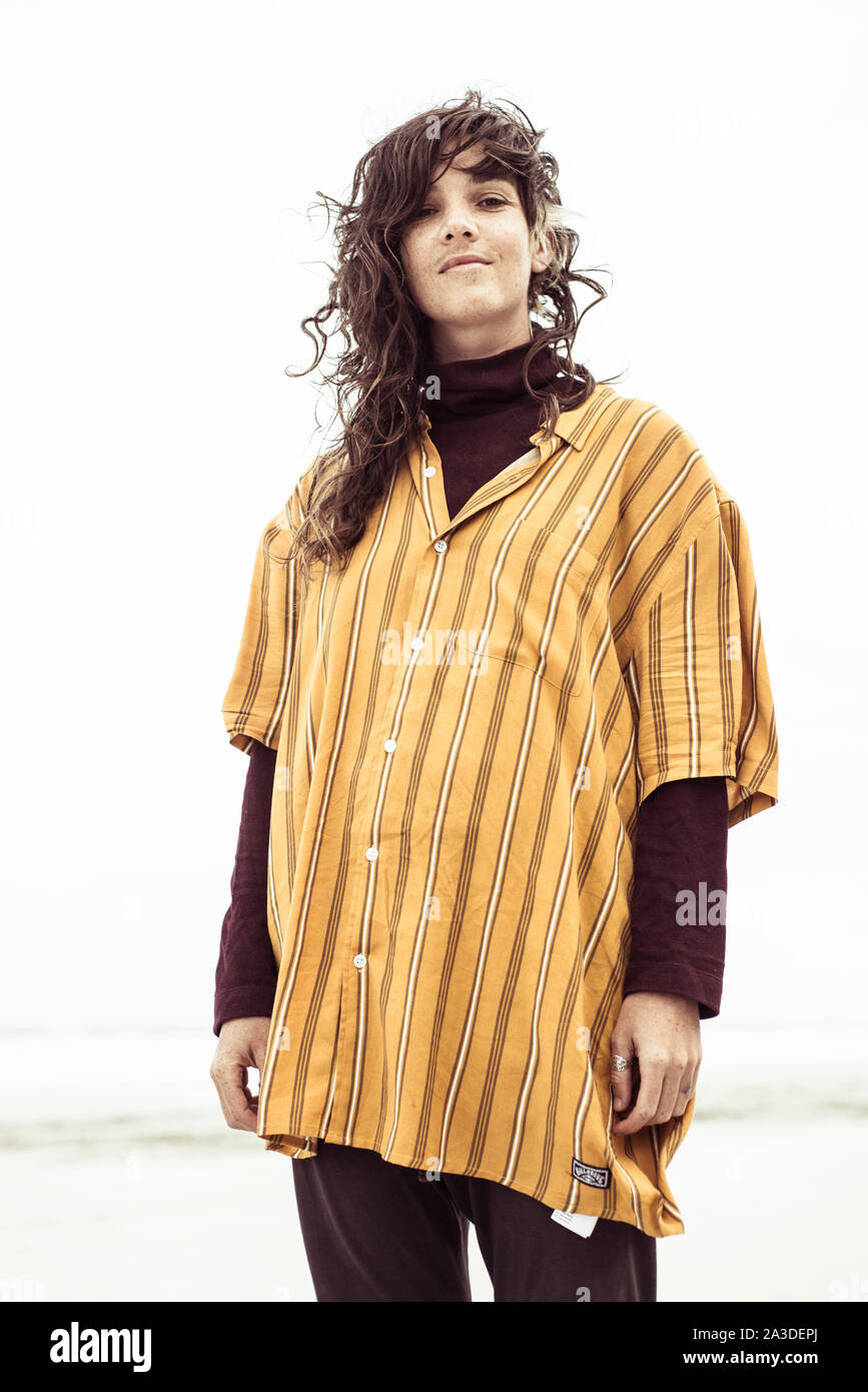 Natürliche junge Frau mit Curly unordentlich Beach Hair lächelt Kamera Stockfoto