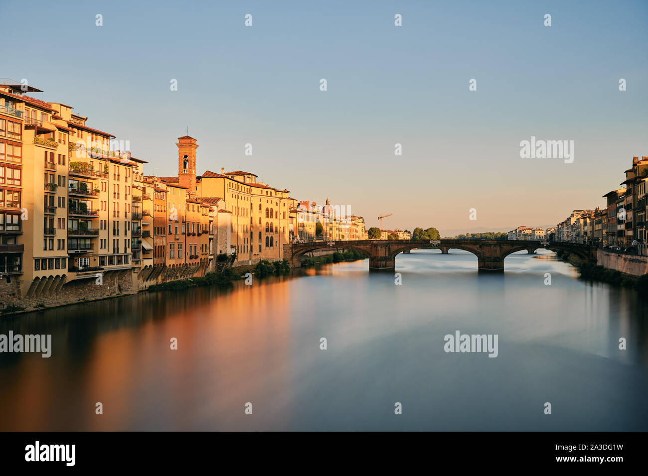 Steinbrücke über die ruhigen Fluss in der Altstadt gegen wolkenlosen Himmel Sonnenuntergang am Abend in der Toskana, Italien. Stockfoto