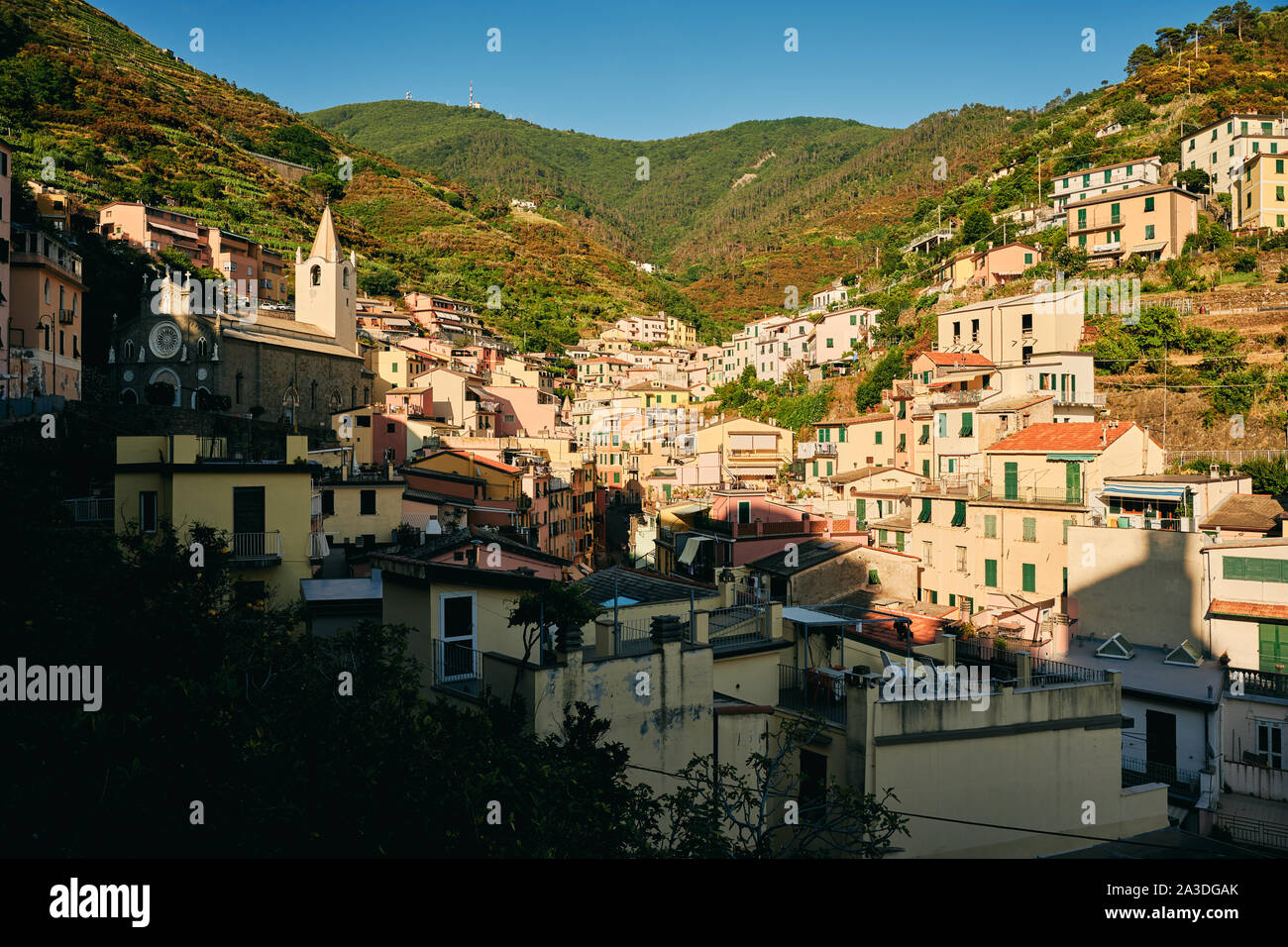 Ruhige, ländliche Stadt mit lebendigen Häuser auf dem grünen Hügel im Sonnenschein in Italien Stockfoto