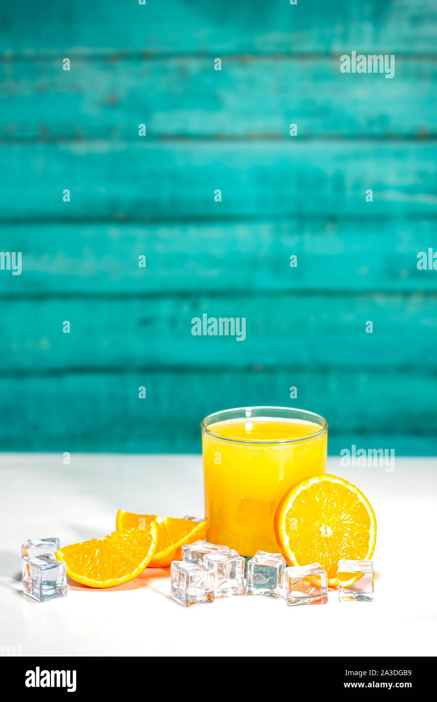 Glas Orangensaft und Orangen auf einem weißen Tisch und die Holzwand mit Platz für Grafiken und Text Stockfoto