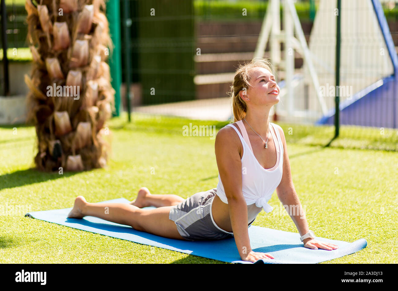 Junge schöne Frau in Sportswear übt Yoga posing außerhalb des Hotels Stockfoto