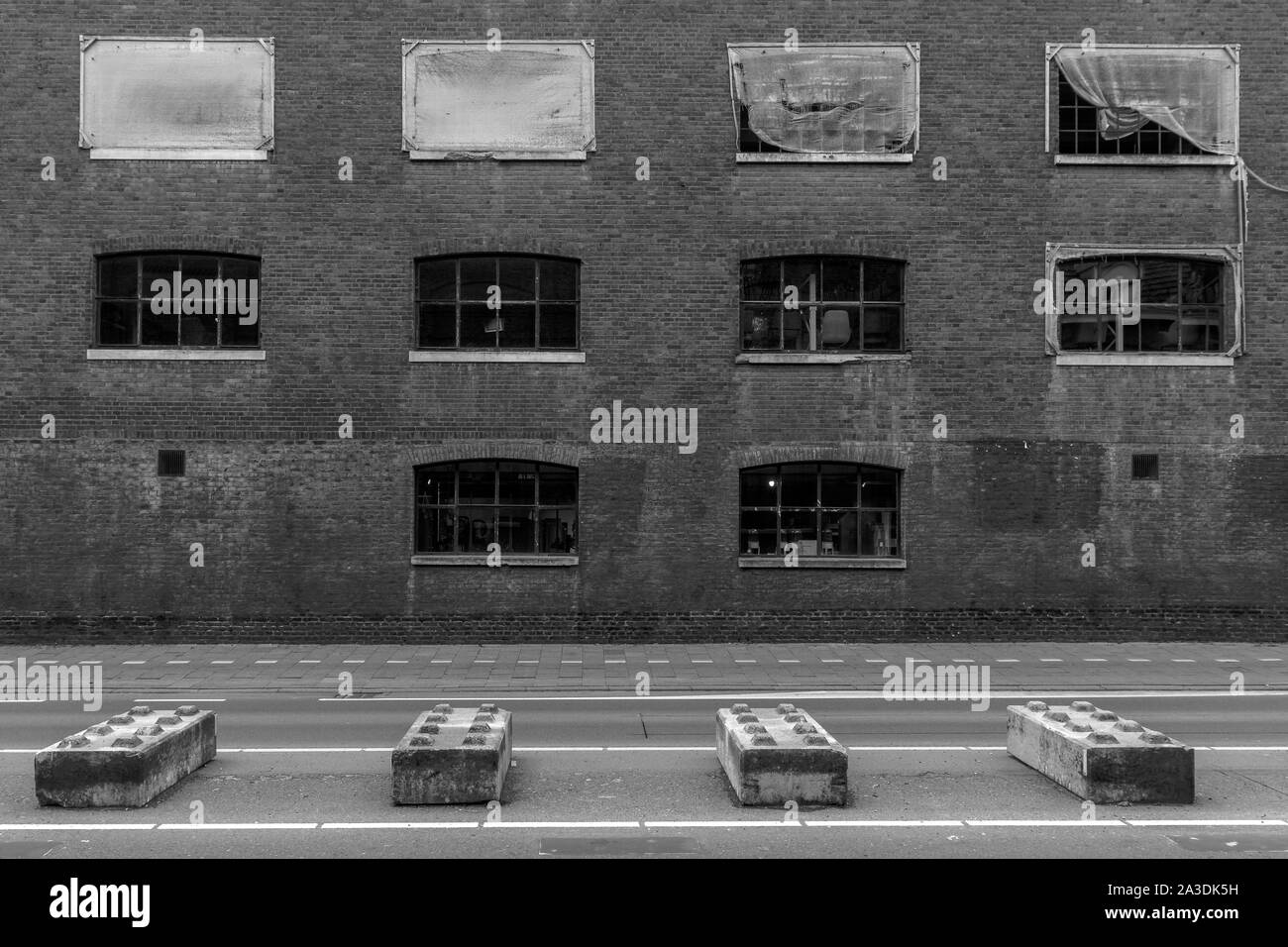 Öffentliche Straße mit Straßensperren in Form von riesigen Lego Bausteine Verkehr mit im Hintergrund auf der alten Fabrik Gebäude getrennt zu halten Stockfoto