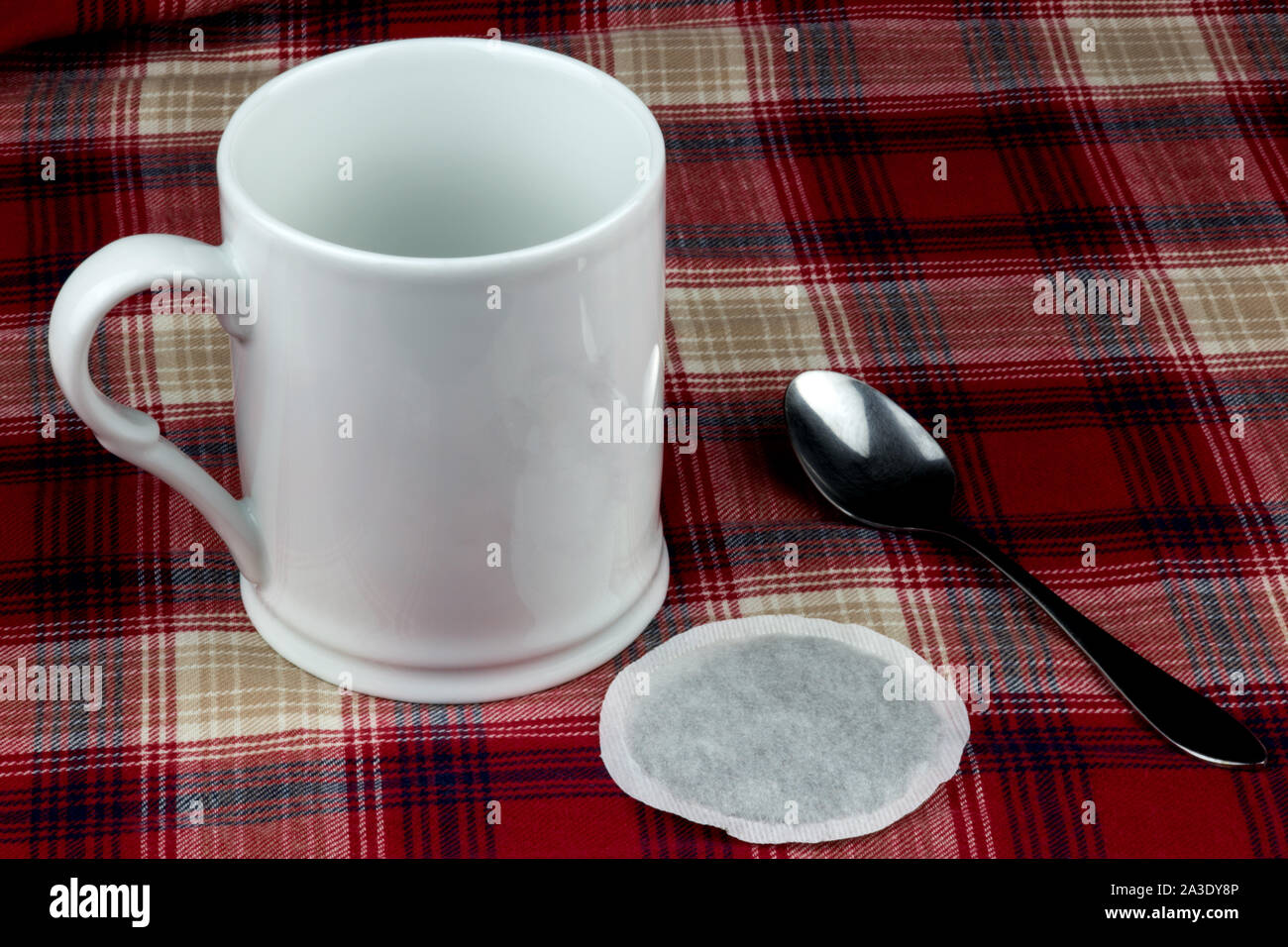 Kaffee Tasse mit Löffel und Tee Beutel auf tartan Tischdecke Stockfoto