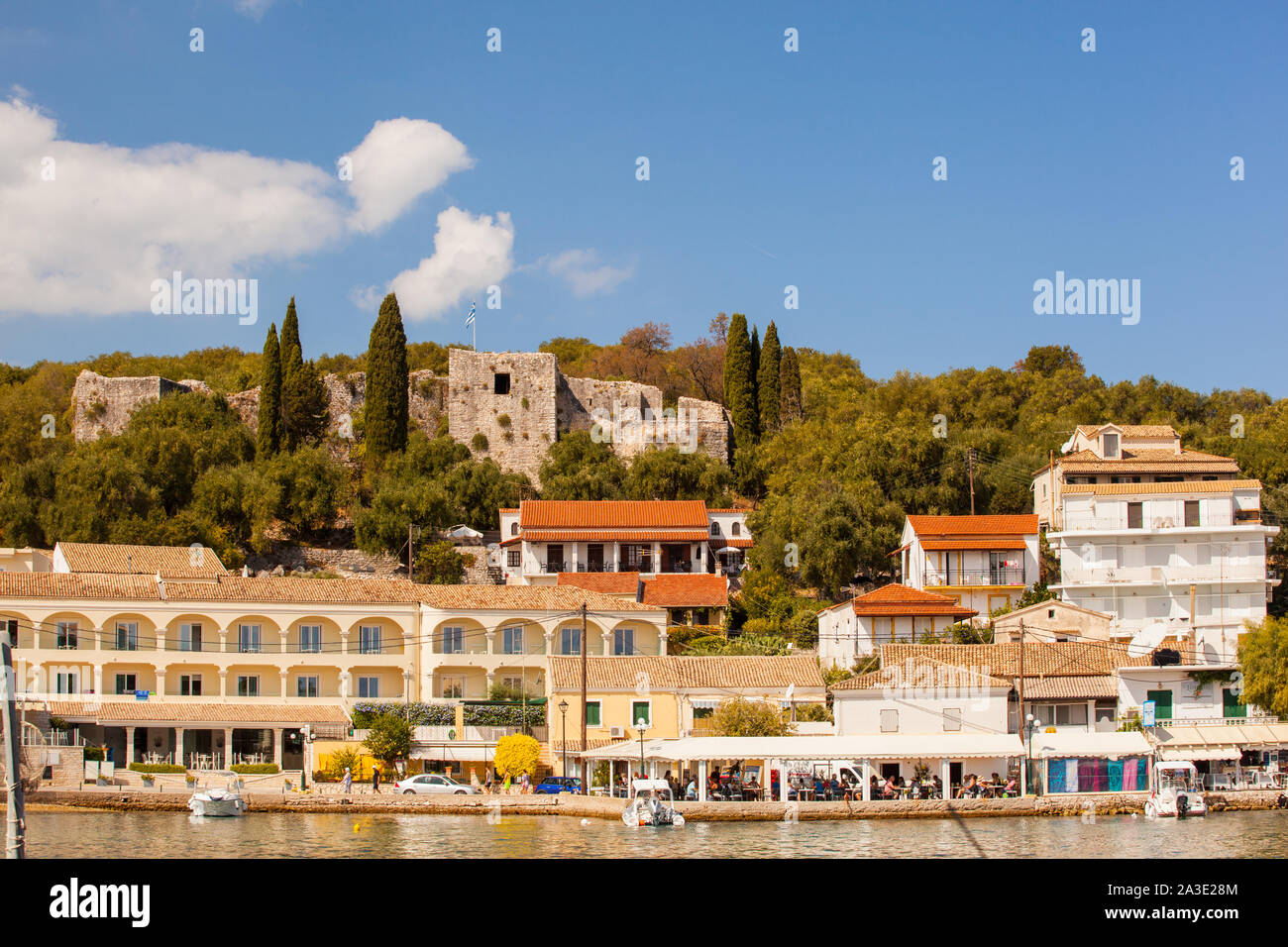 Blick auf den Hafen und die Wasserseite Bars und Tavernen in der Griechischen Seaside Holiday Resort von Kassiopi auf der Insel Korfu in Griechenland mit seinem Schloss Stockfoto