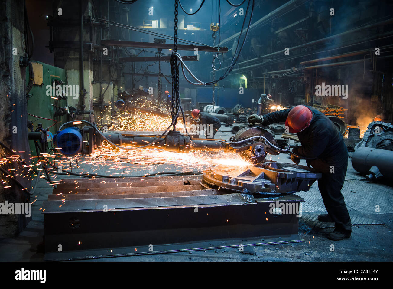 Hand in Handschuhe hält die Winkelschleifer und Sägen das Metall von einer Person Gesicht nicht sehen können Funken fliegen. Stockfoto
