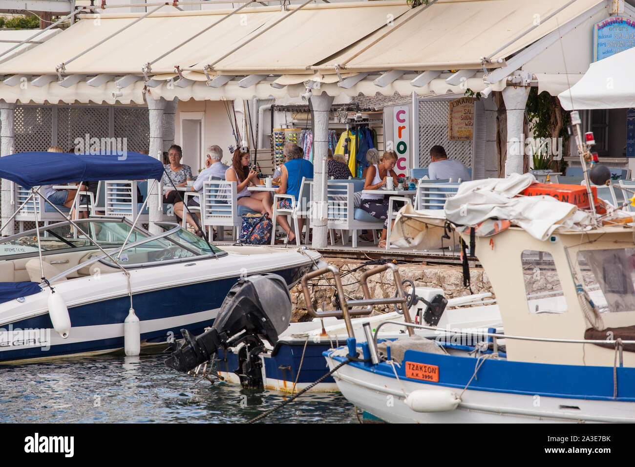 Leute, Touristen und Urlauber Essen und Trinken in den Cafes und Bars rund um den Hafen an der griechischen Ferienort Kassiopi Korfu Griechenland Stockfoto