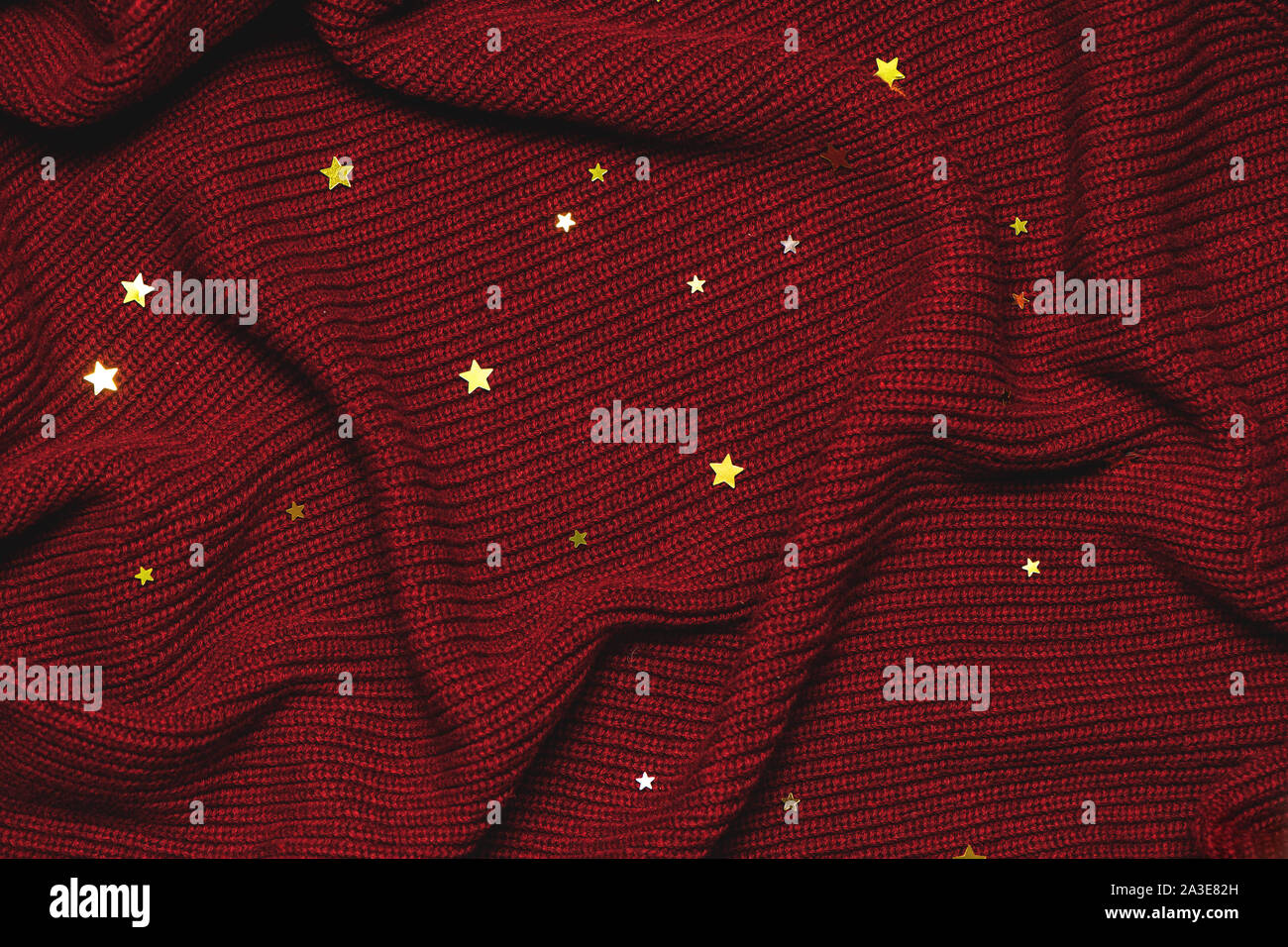 Weihnachten Hintergrund mit den goldenen Sternen auf rotem gemütlichen Pullover. Ansicht von oben. Stockfoto