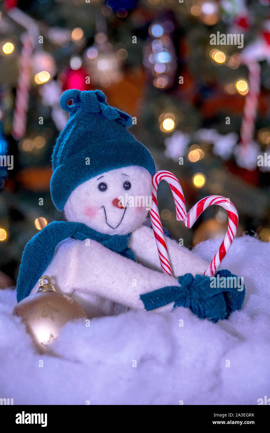 Gefüllte Schneemann in eine blaue Mütze und Schal, hält Zuckerstangen in der Form eines Herzens Stockfoto